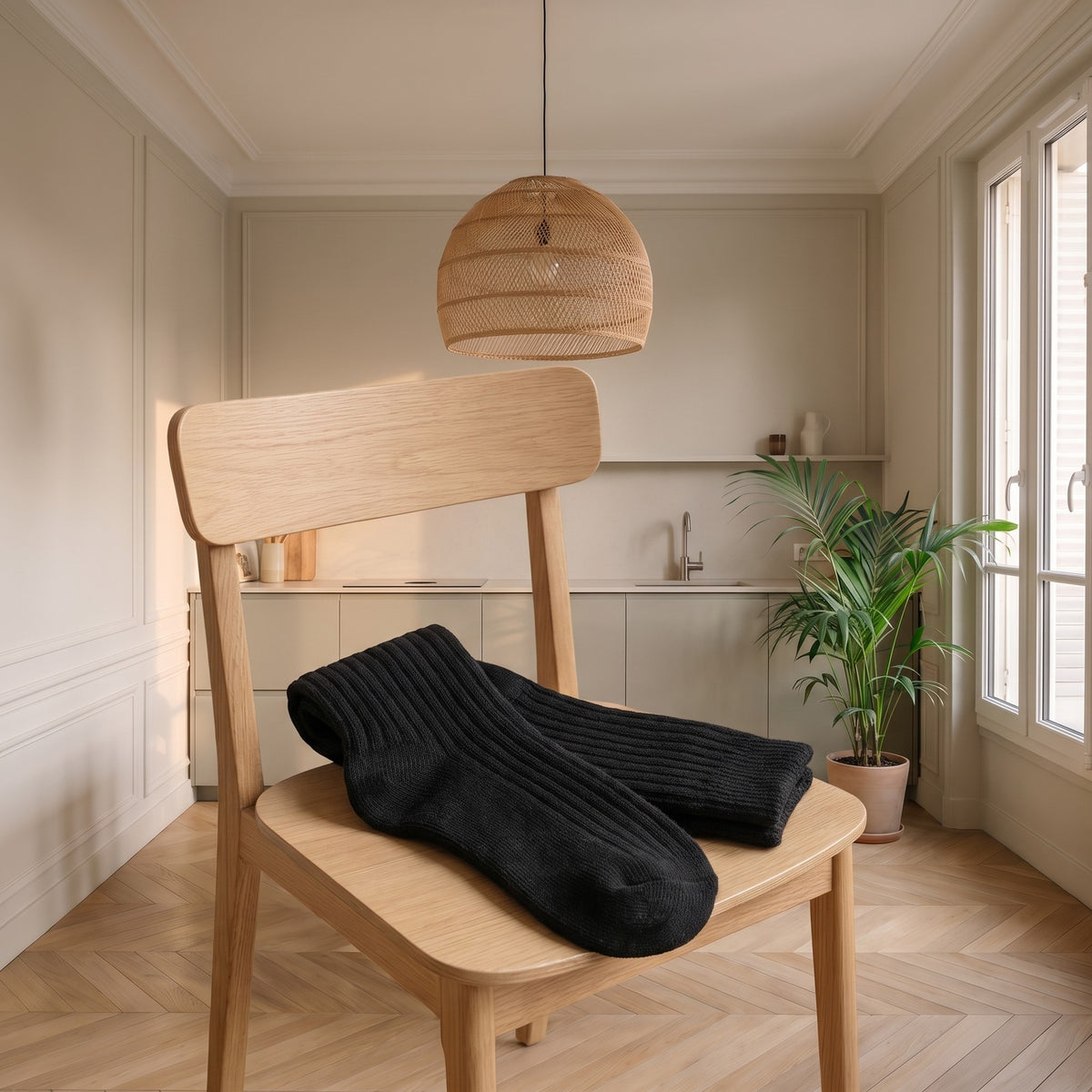 Paire de chaussettes hautes côtelées noire posée sur une chaise en bois clair