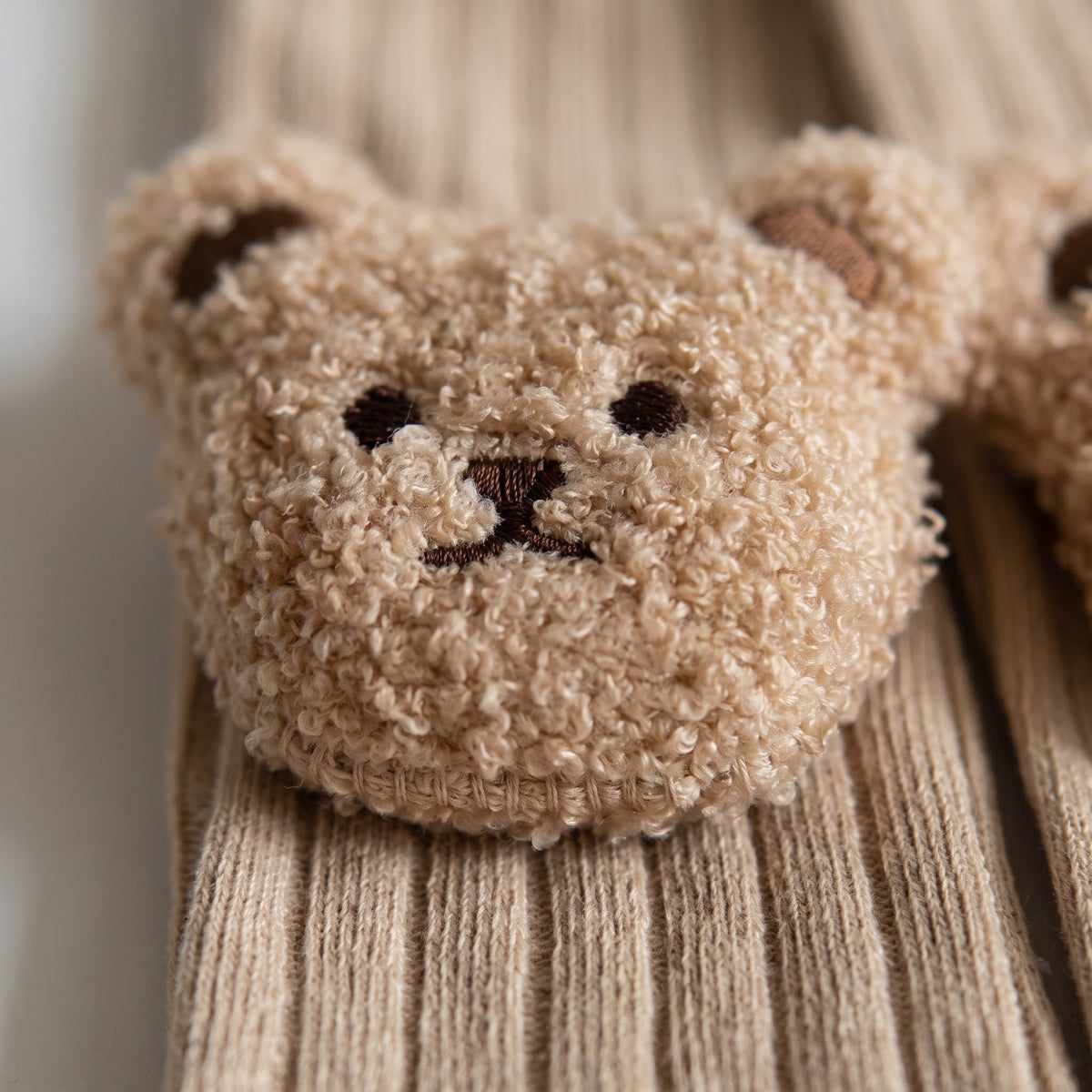 La couture qui attache la tête d'ourson en peluche au bord côtelé de la chaussette Image