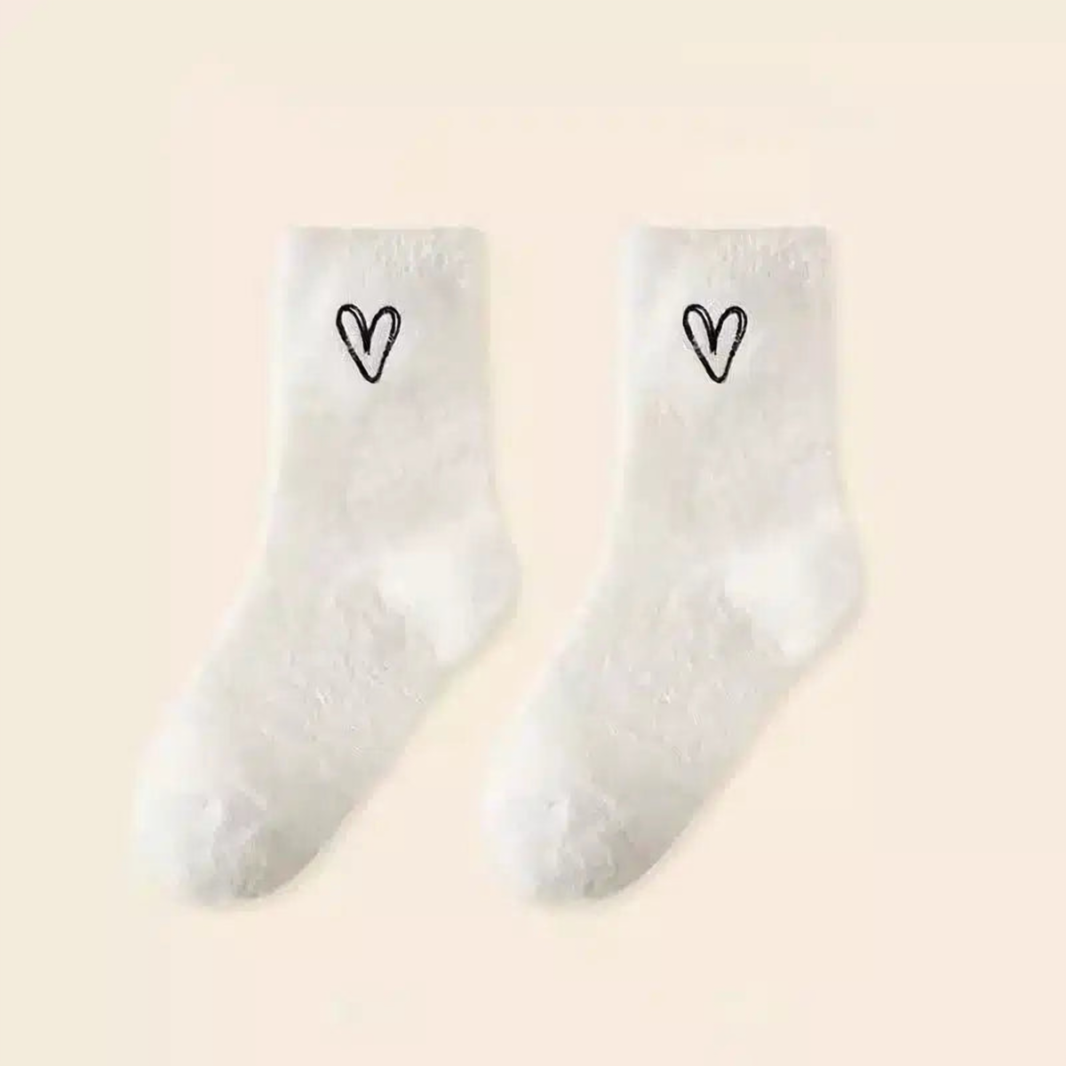 Une paire de chaussettes peluche blanches à cœur brodé noir