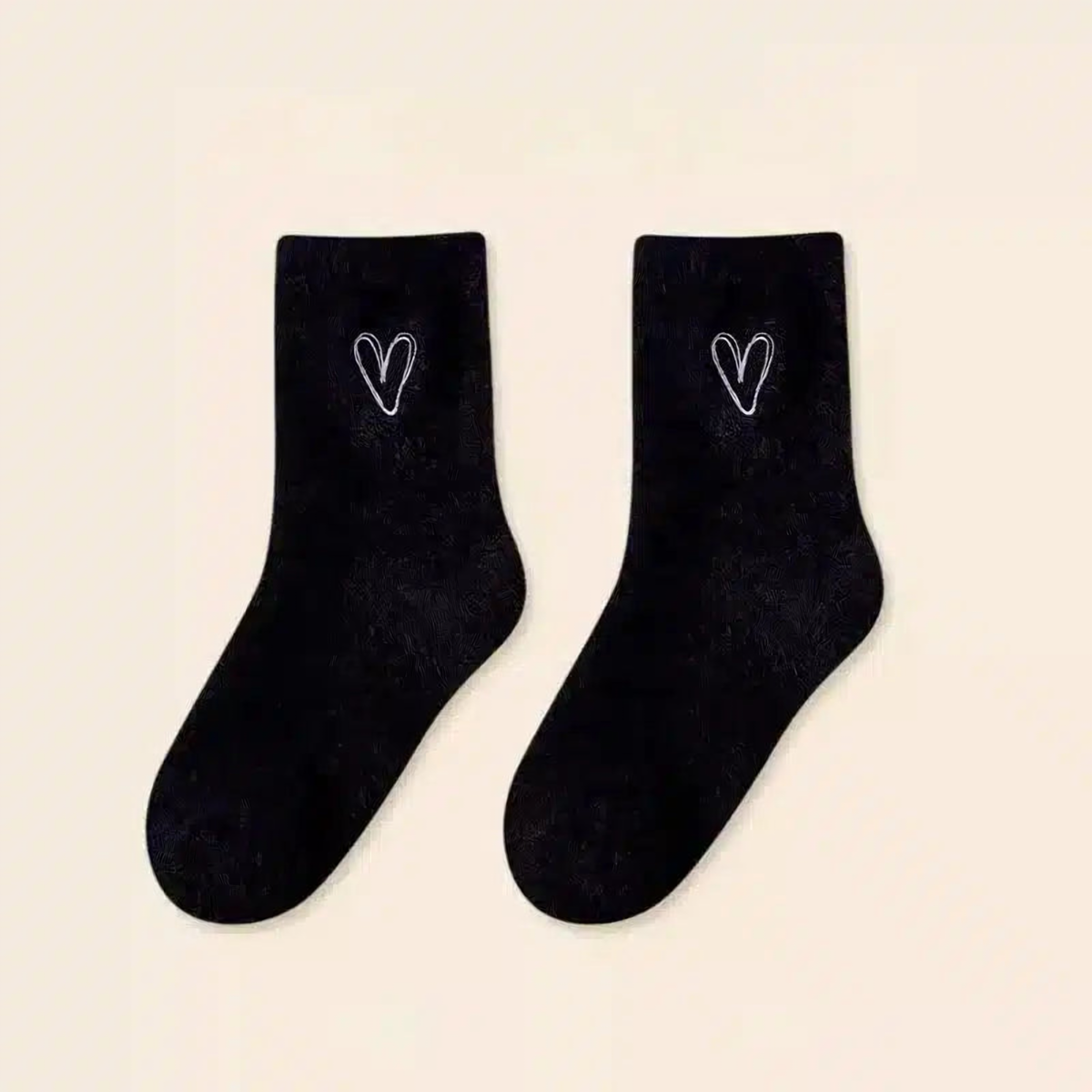 Une paire de chaussettes peluche noires à cœur brodé blanc