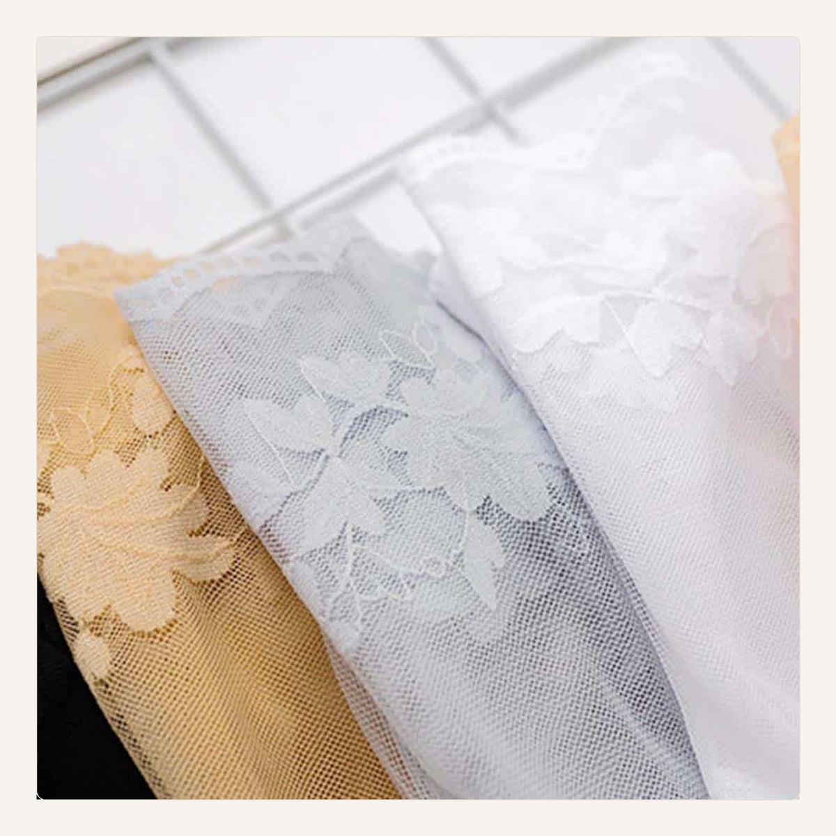 Gros plan des fleurs sur trois chaussettes transparentes beige, grise et blanche