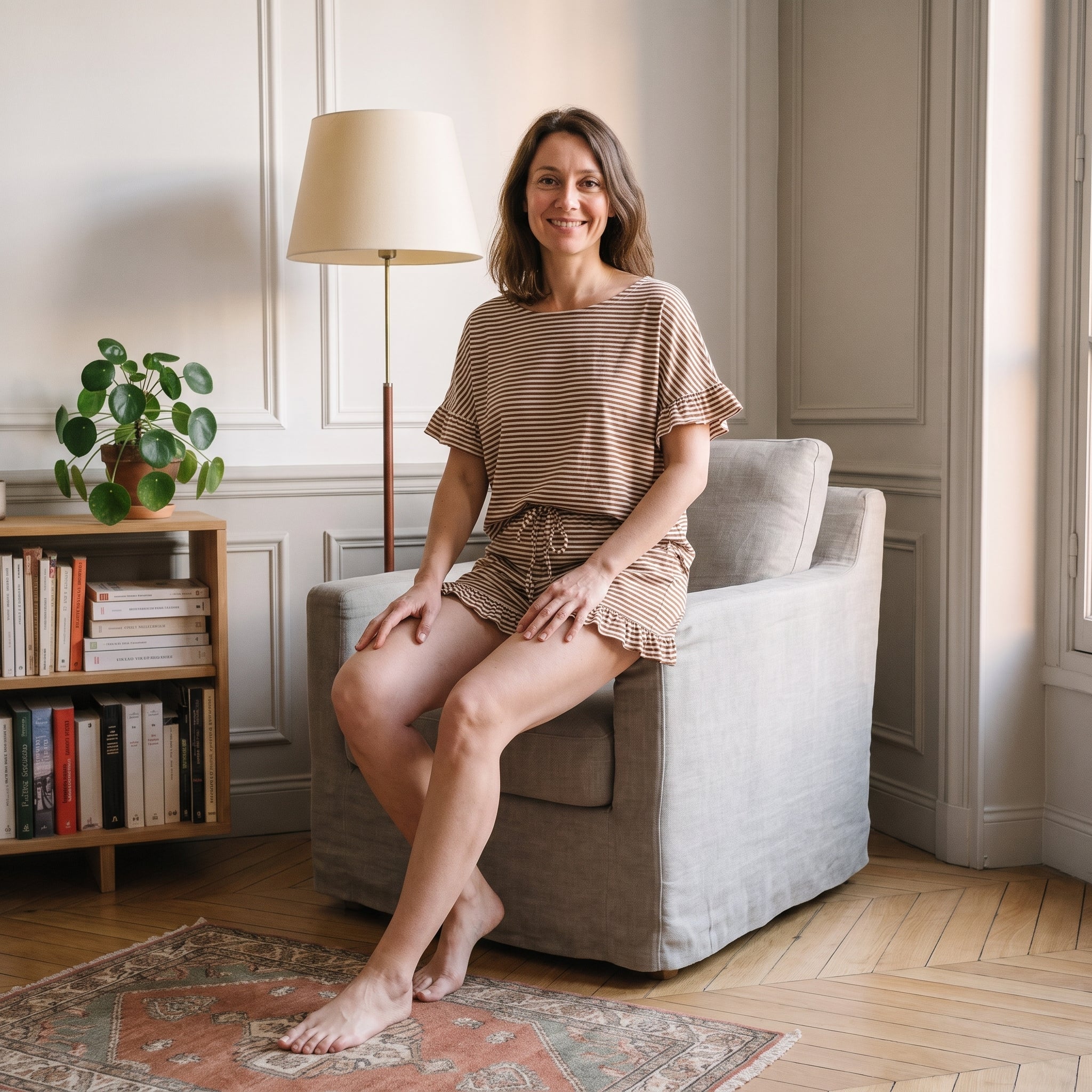 Femme assise dans un fauteuil en ensemble pyjama d'été à rayures beiges Image