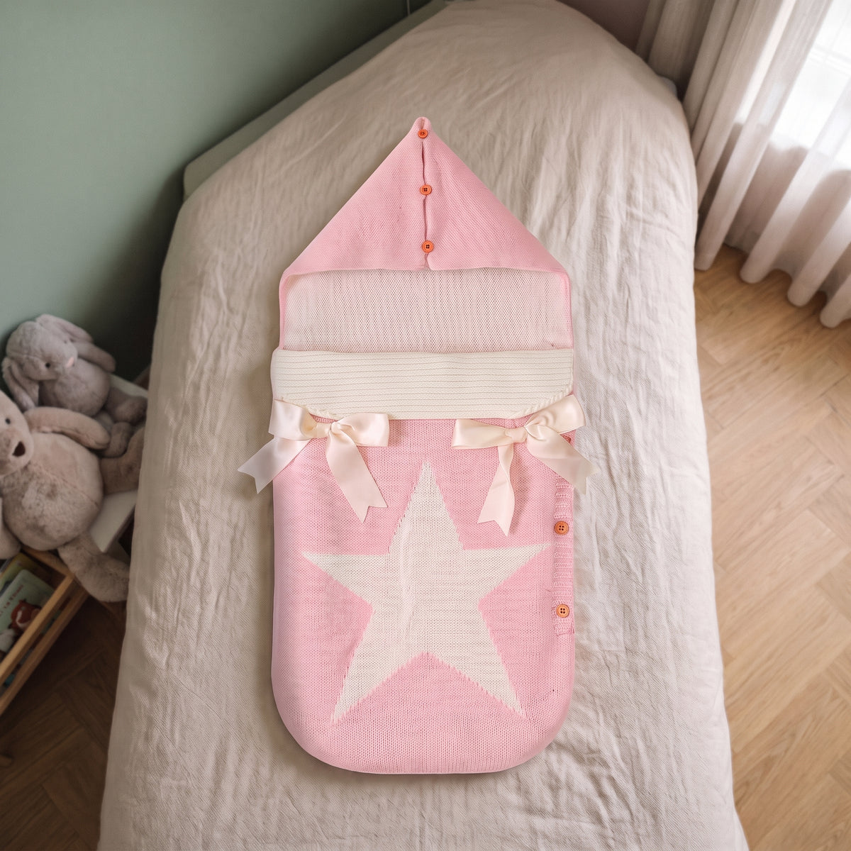 Gigoteuse bébé rose poudré refermée, posée à plat sur le lit d'une chambre d'enfant Image