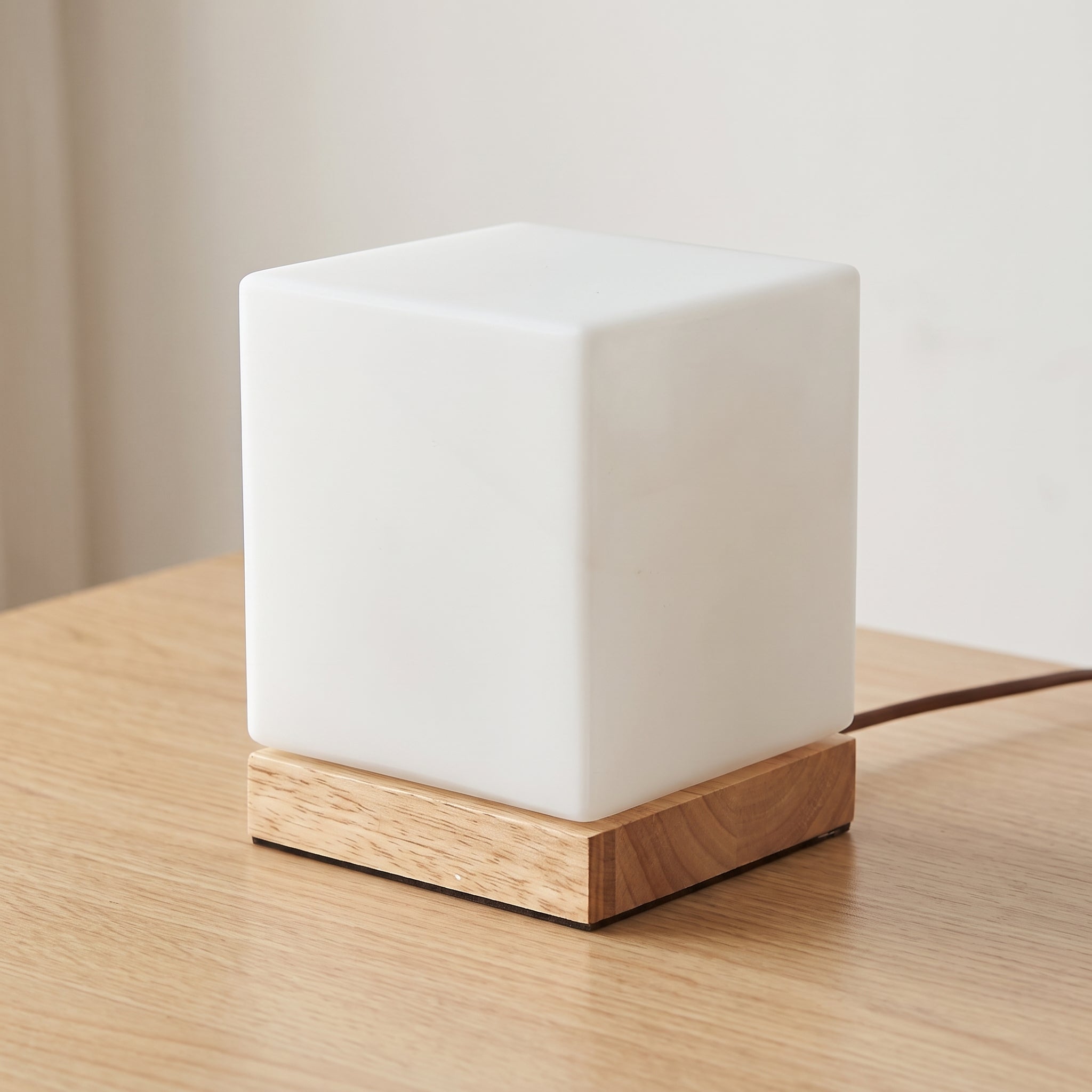 Lampe de chevet cube en bois posée sur un plateau de chêne Image