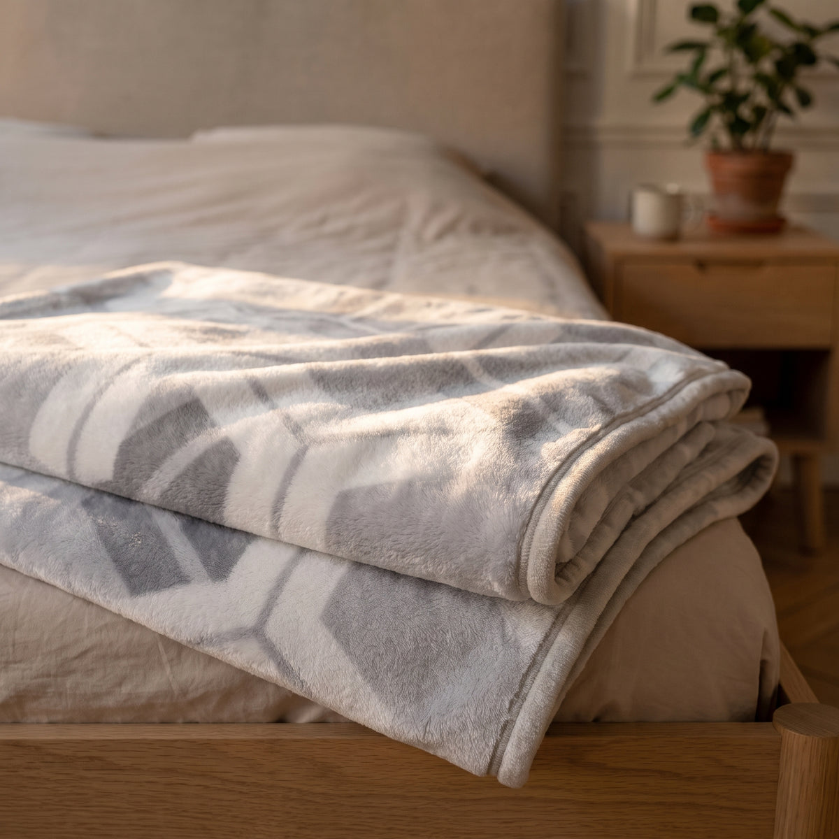Plaid polaire à motifs replié au pied d'un lit, poil ras en lumière rasante Image