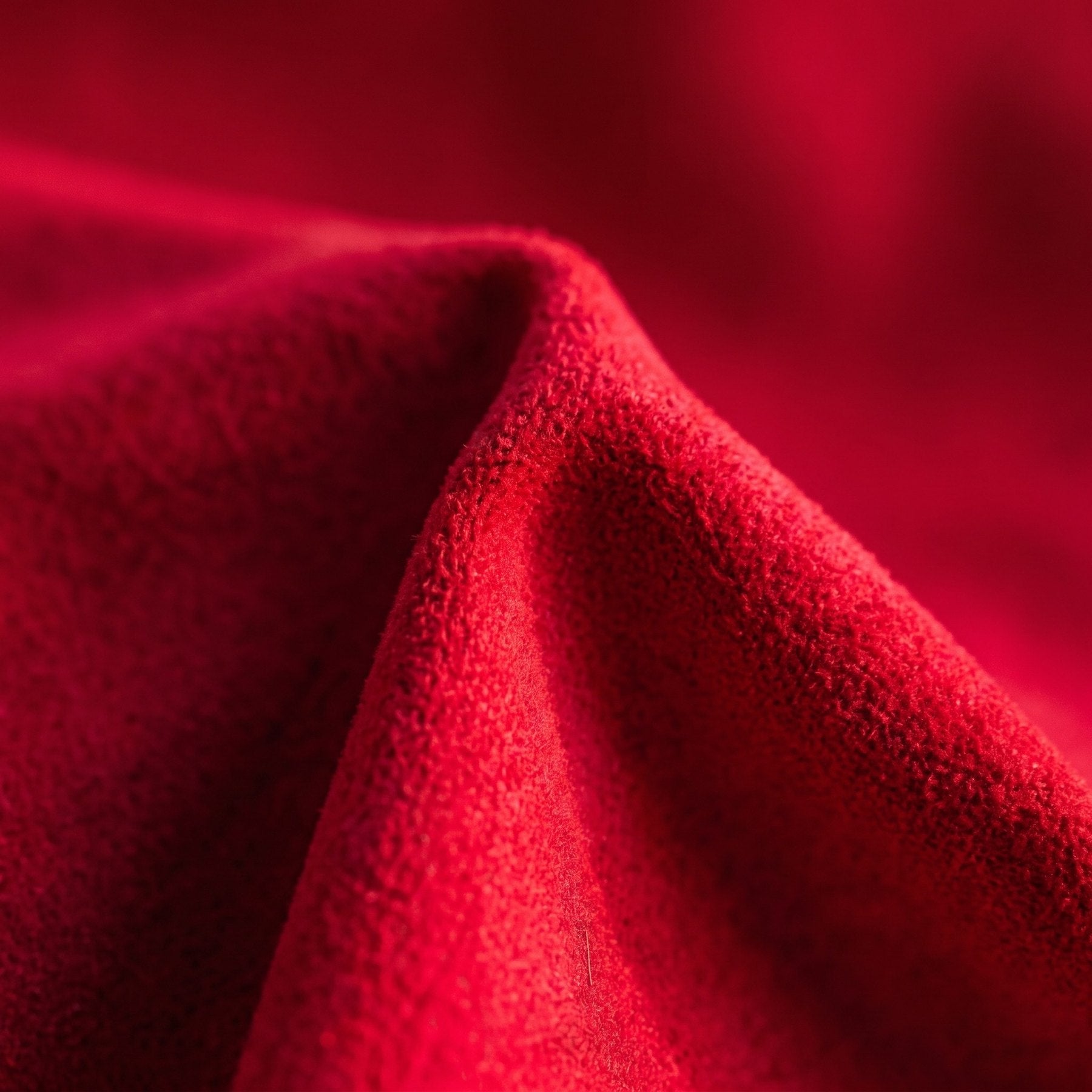 Pli de la microfibre suédine rouge du pouf en lumière rasante Image