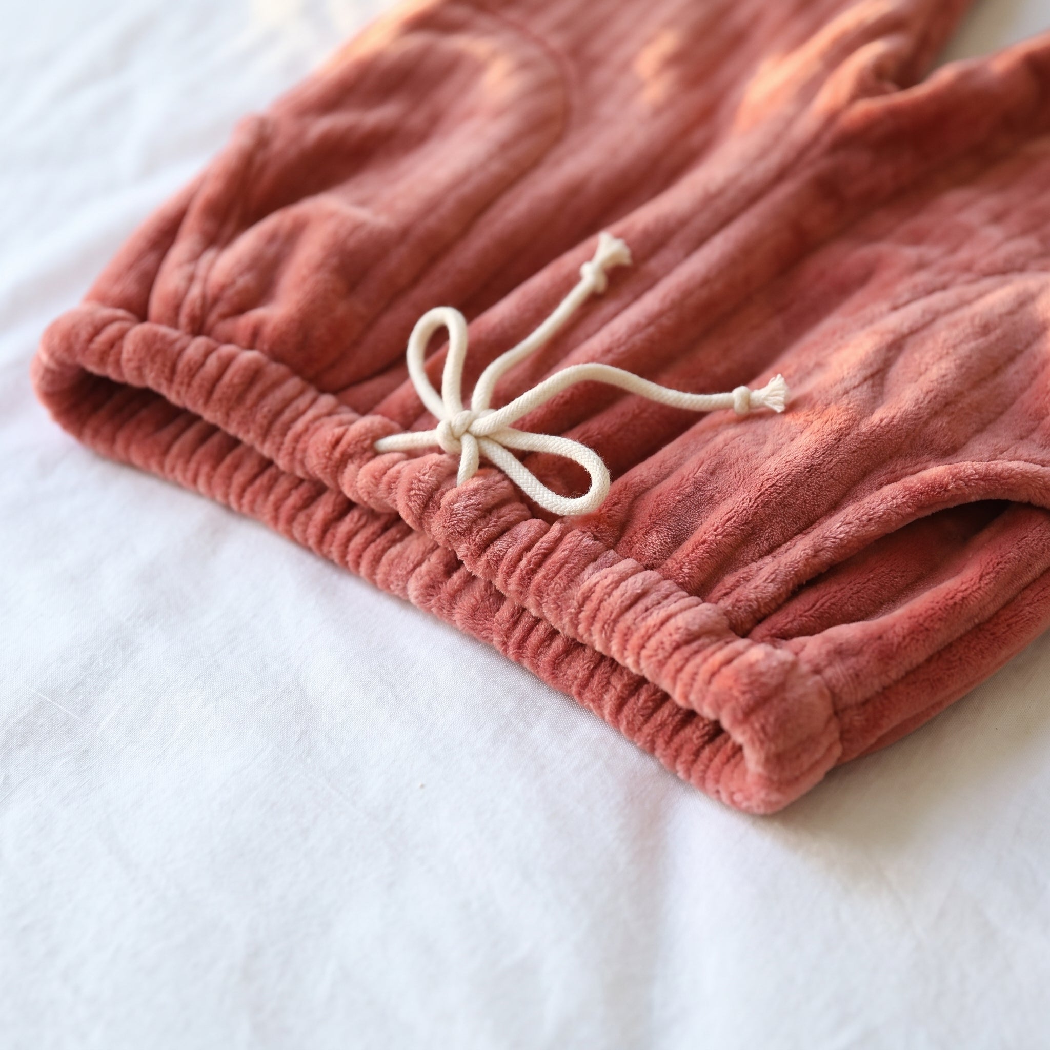 Détail de la taille du pantalon : ceinture élastiquée et cordon de serrage noué, coloris rouge brique. Image