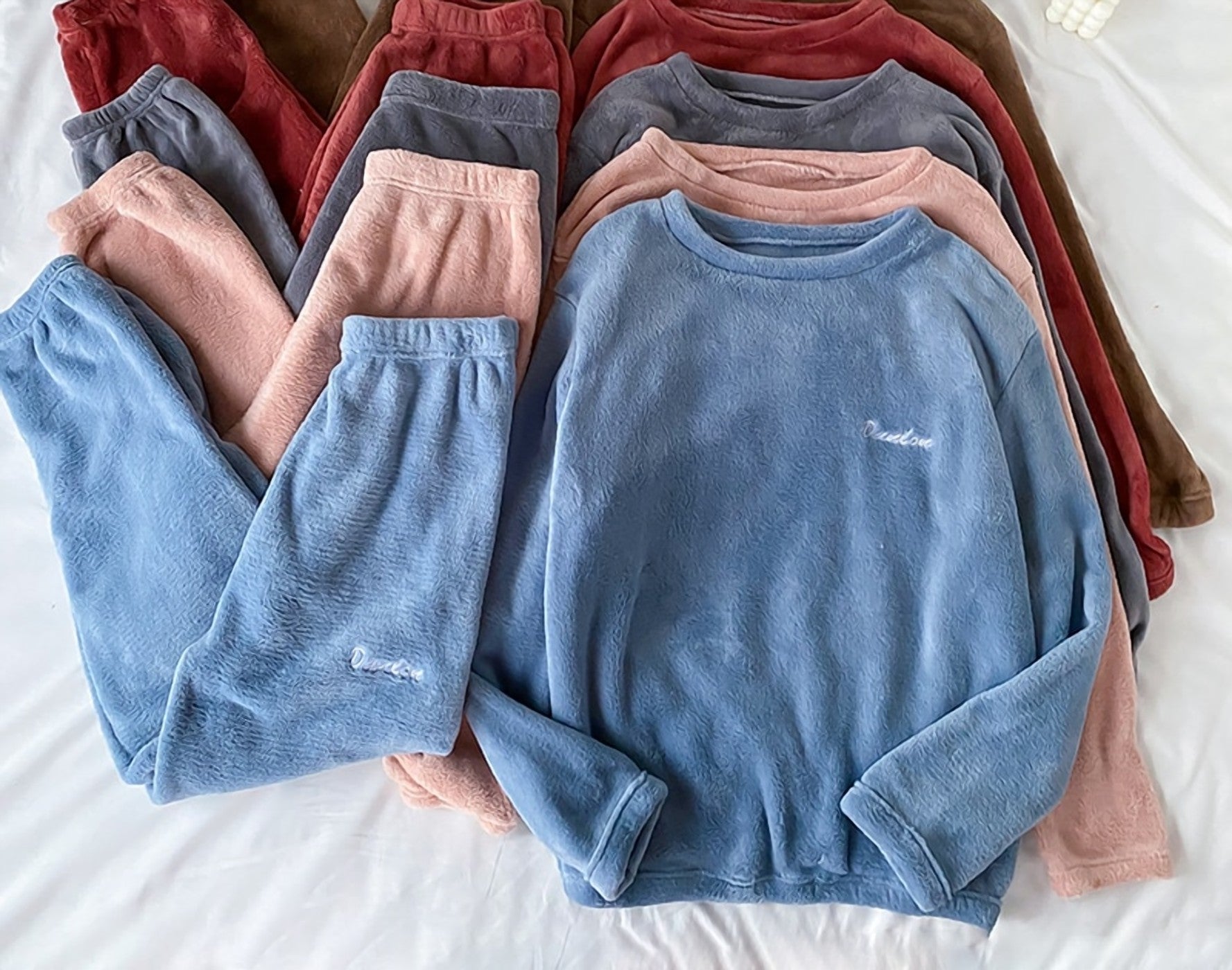Plusieurs coloris du pyjama en velours pliés côte à côte sur un lit Image