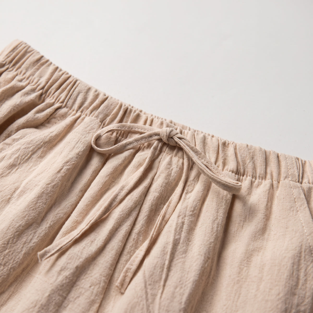 Ceinture élastique froncée et lien plat noué d'un short en coton et lin beige Image