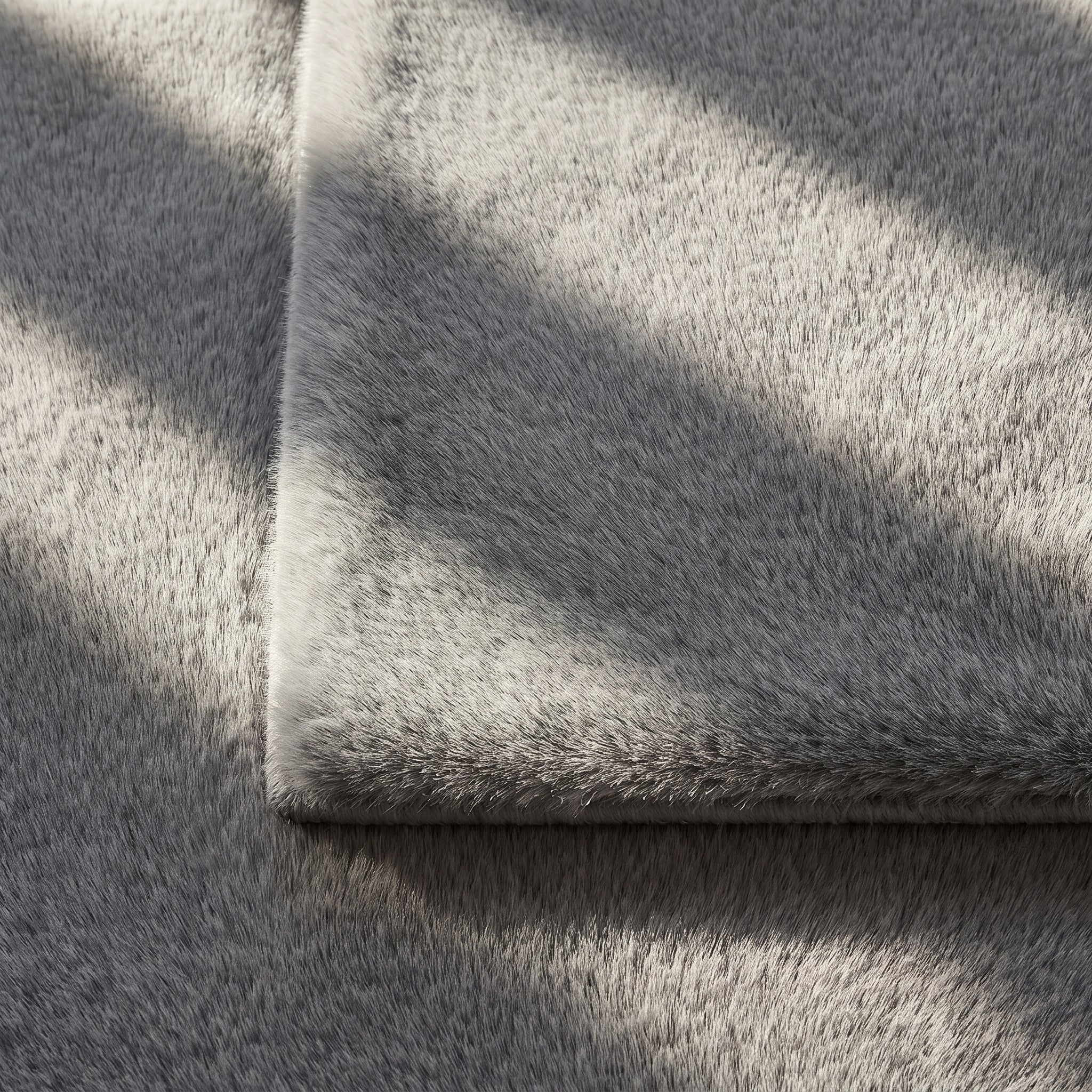Gros plan de la fourrure synthétique grise du tapis, poil ras traversé par la lumière Image