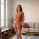 Ensemble d'été en éponge pour femme, coloris terracotta, t-shirt et short portés dans un salon