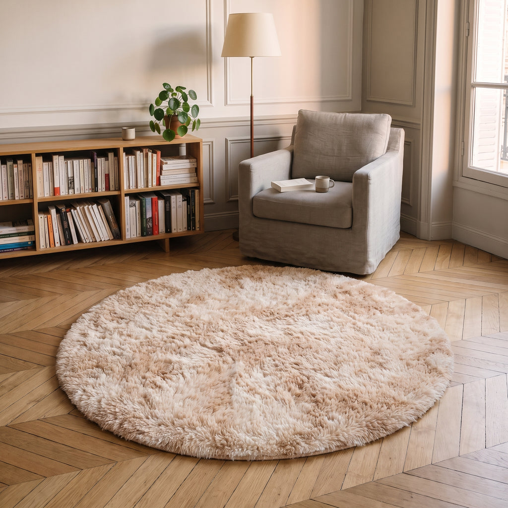 Tapis rond à poils longs coloris Beige rosé, posé devant le fauteuil d'un coin lecture