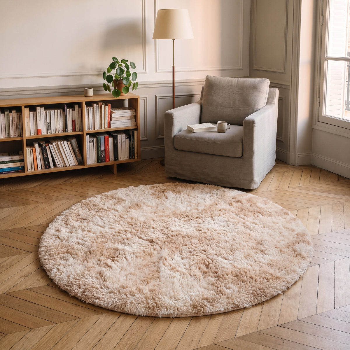 Tapis rond à poils longs coloris Beige rosé, posé devant le fauteuil d'un coin lecture