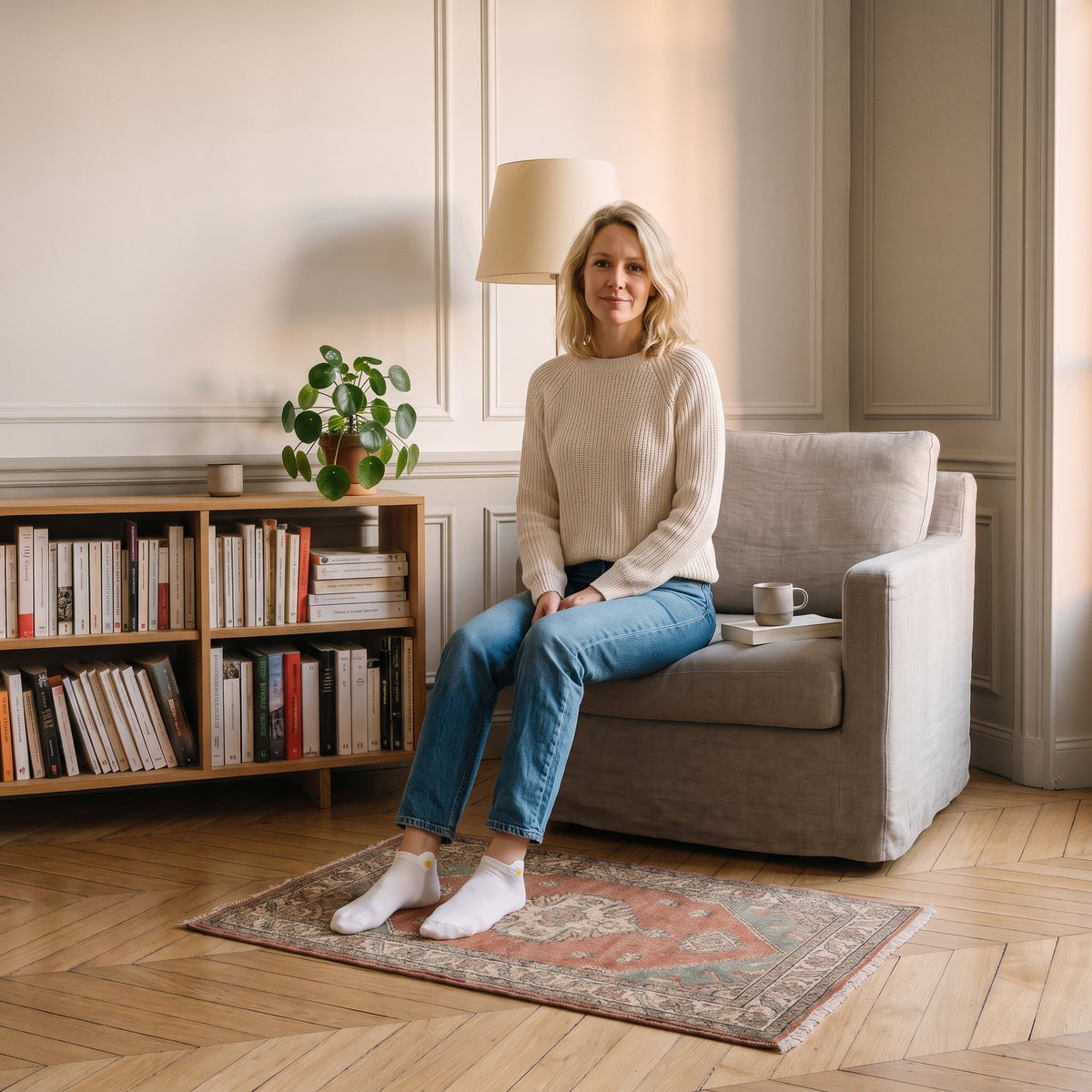 Chaussettes basses blanches à marguerite brodée portées aux pieds dans un coin lecture