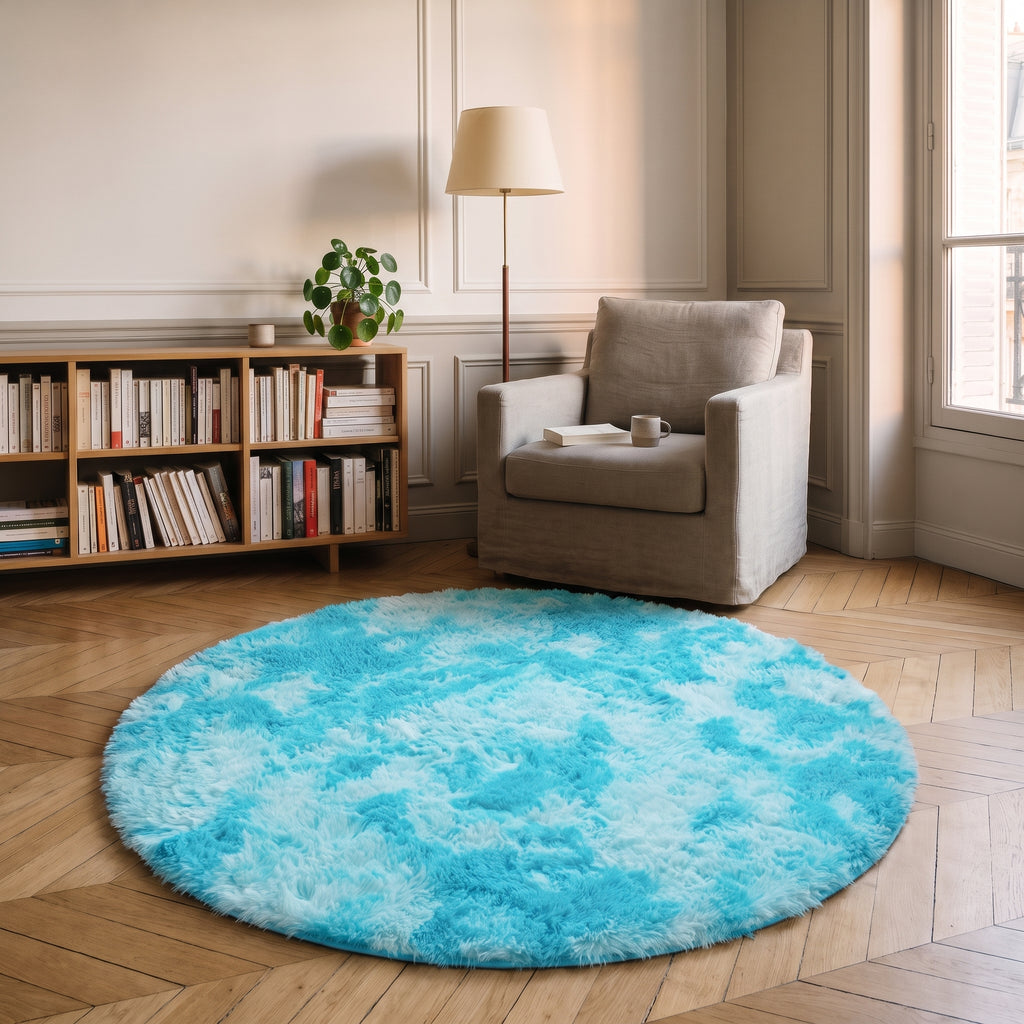 Tapis rond à poils longs coloris Bleu clair, posé devant le fauteuil d'un coin lecture