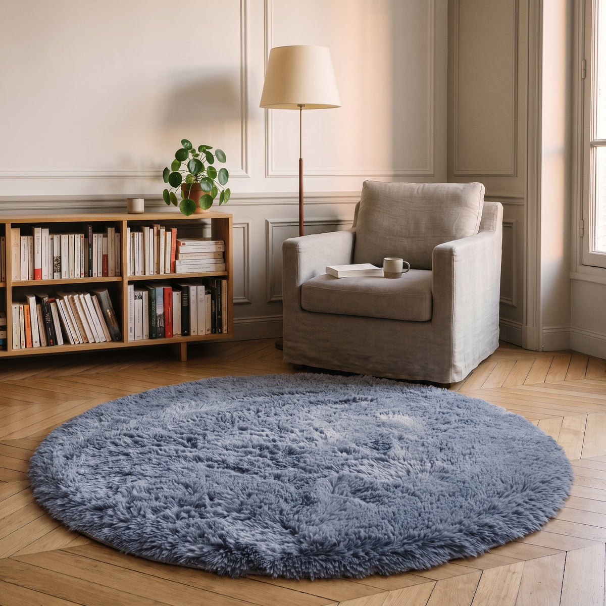 Tapis rond à poils longs coloris Gris anthracite, posé devant le fauteuil d'un coin lecture