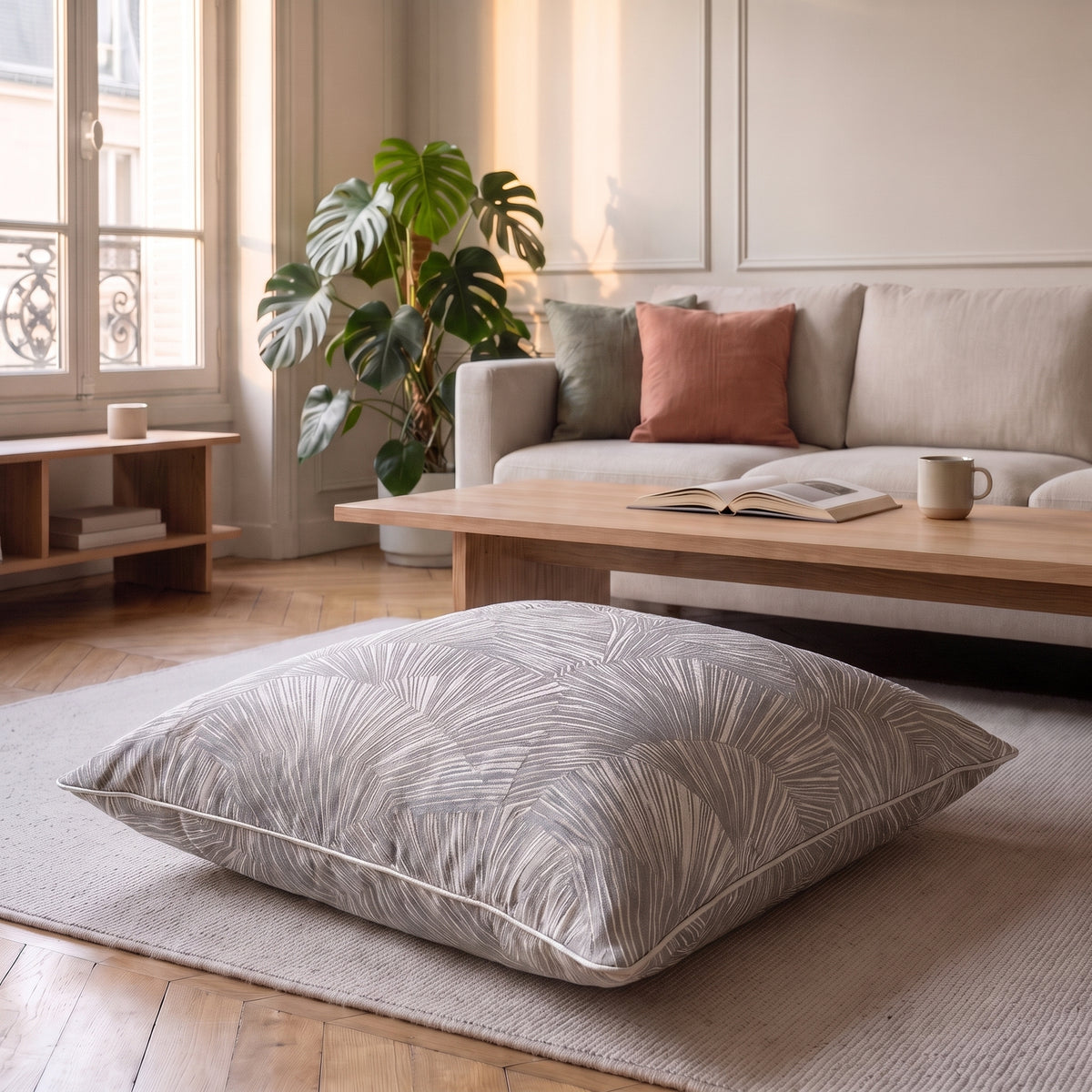 Coussin jacquard satiné gris perle aux palmes posé sur un fauteuil