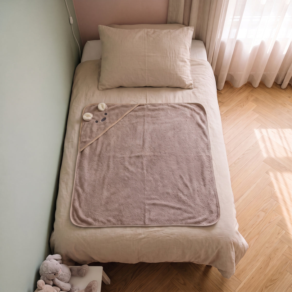 Cape de bain bebe 90 x 90 cm coloris marron, capuche souris, depliee sur le lit d enfant