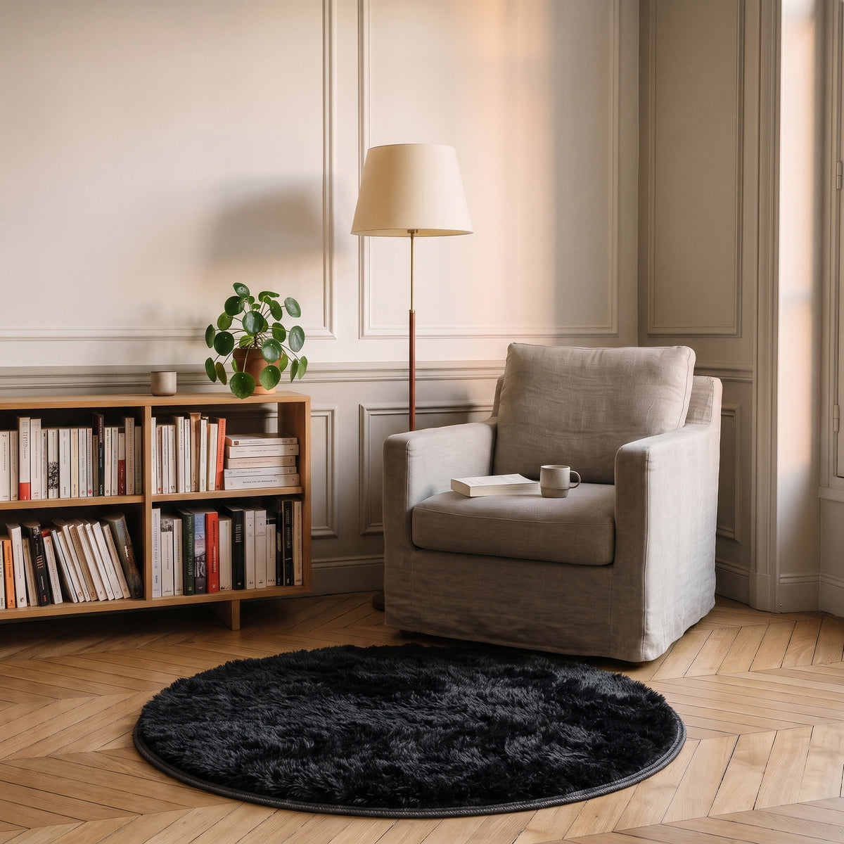 Tapis rond à poils longs coloris Noir, posé devant le fauteuil d'un coin lecture