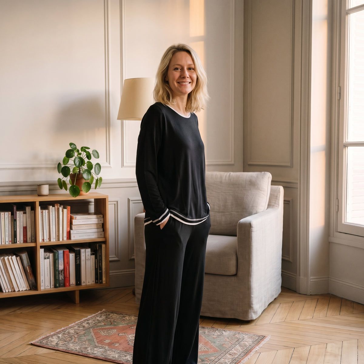 Pyjama coton et modal noir porté par une femme dans un coin lecture