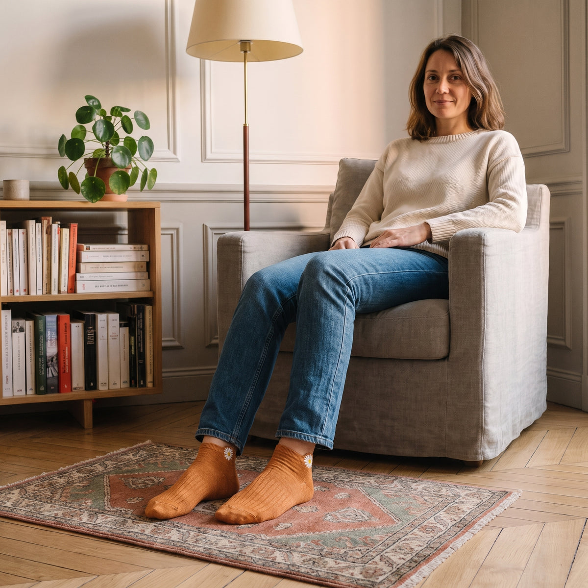 Chaussettes basses orange à marguerite brodée portées aux pieds dans un coin lecture
