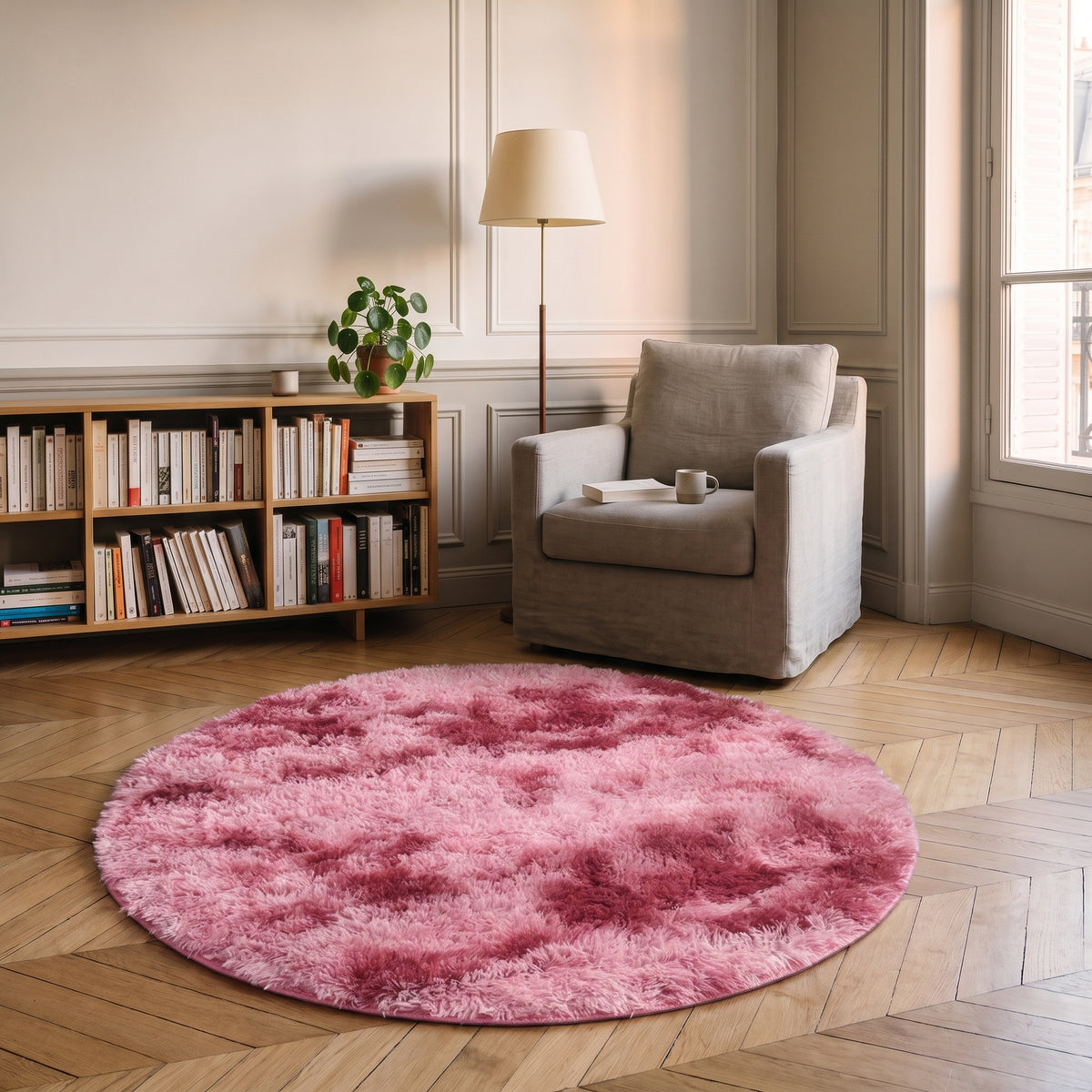 Tapis rond à poils longs coloris Rouge, posé devant le fauteuil d'un coin lecture