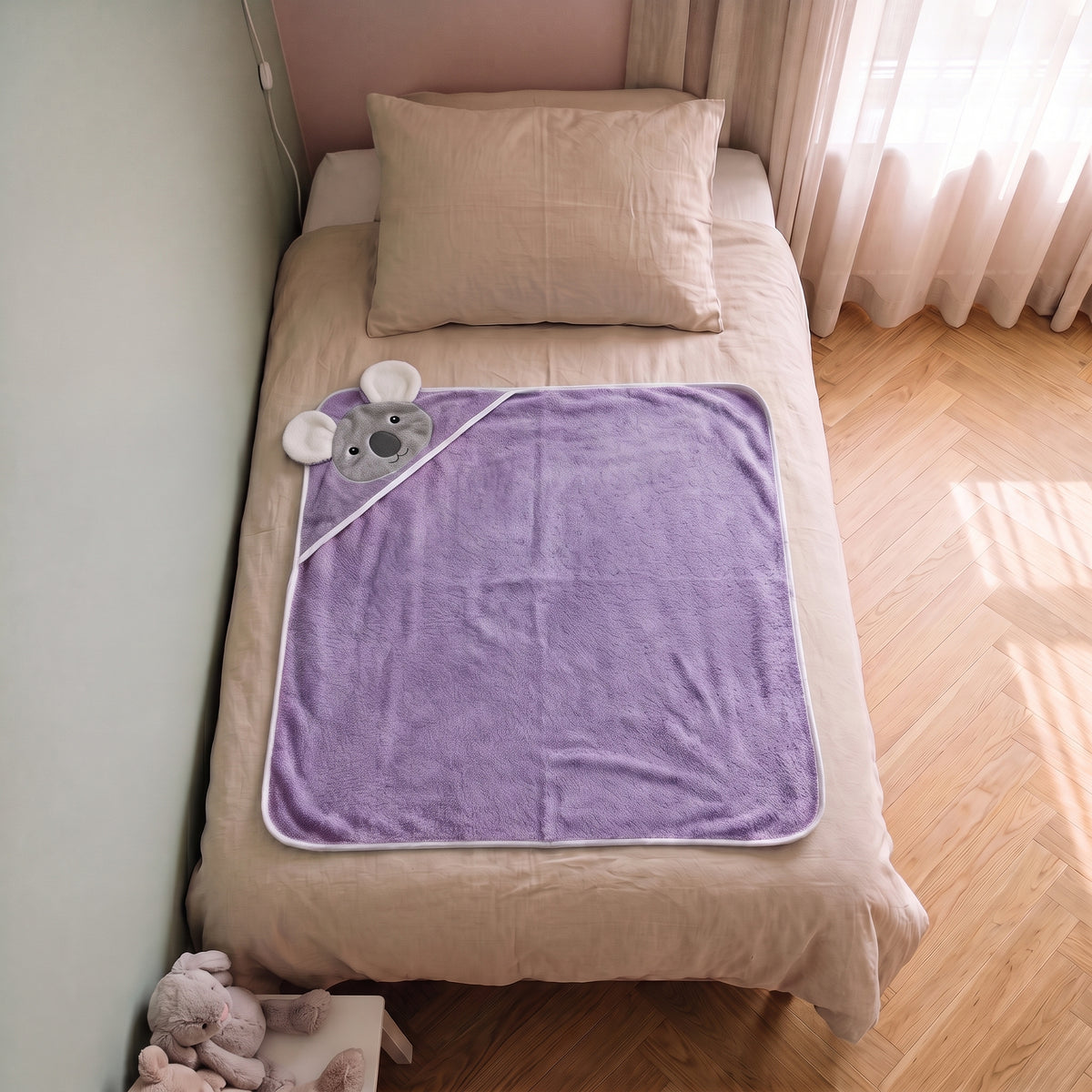Cape de bain bebe 90 x 90 cm coloris violet parme, capuche koala, depliee sur le lit d enfant