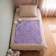 Cape de bain bebe 90 x 90 cm coloris violet parme, capuche koala, depliee sur le lit d enfant