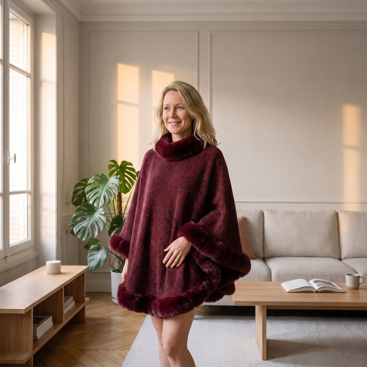 Poncho femme épais bordeaux porté près d'une fenêtre dans un salon