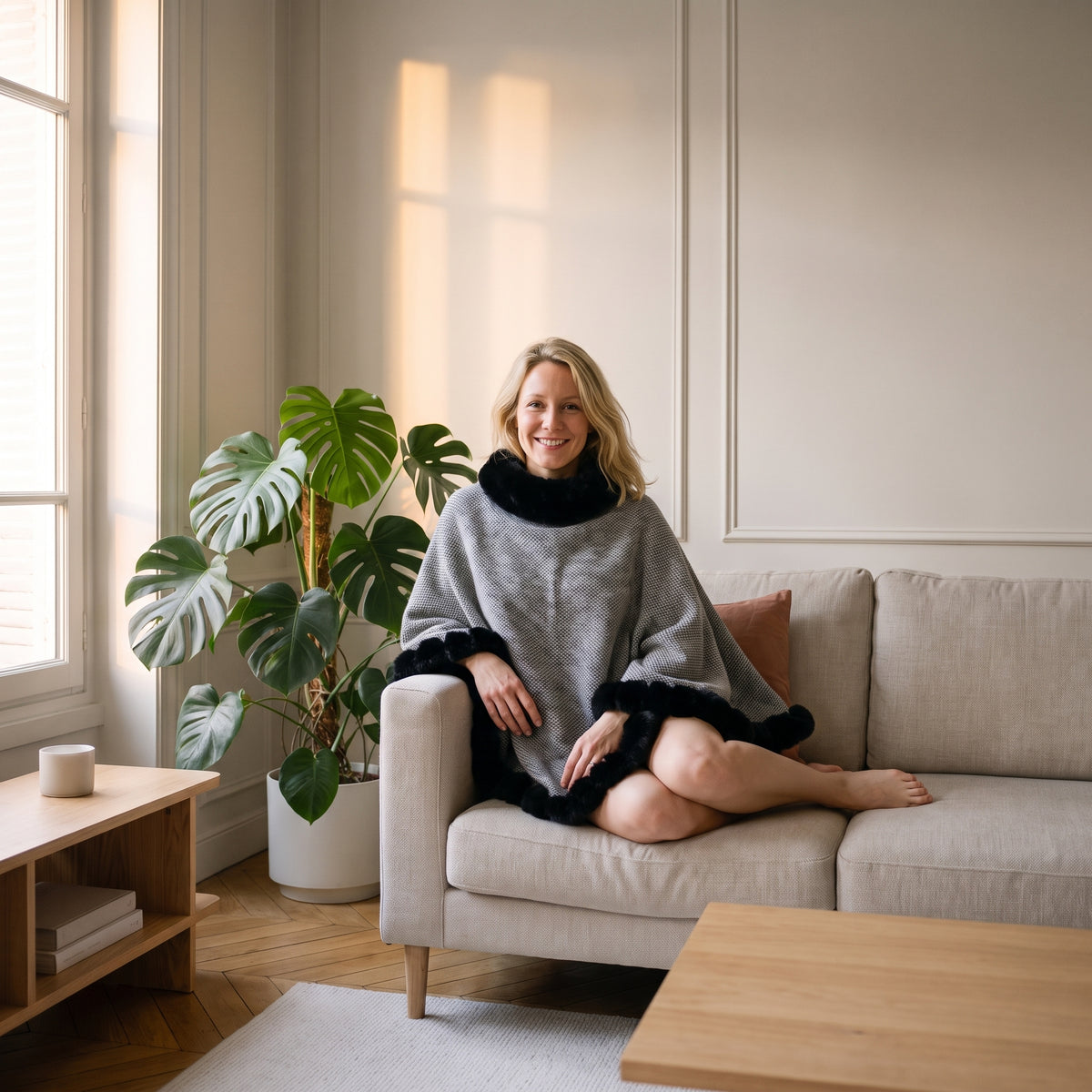 Poncho femme épais gris clair porté, assise sur un canapé de salon