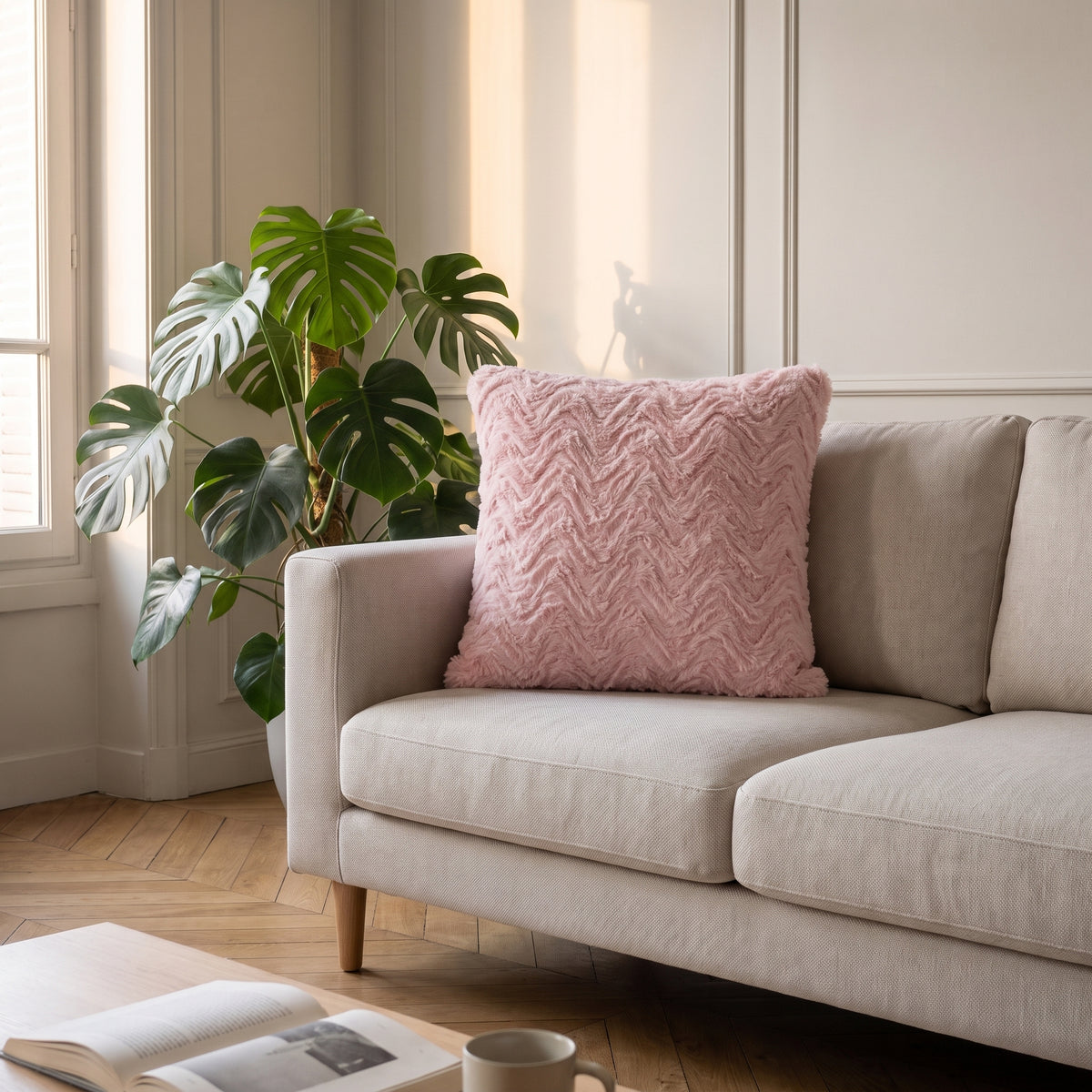 Coussin en coton rose poudré à poil long posé contre le dossier d'un canapé clair Image