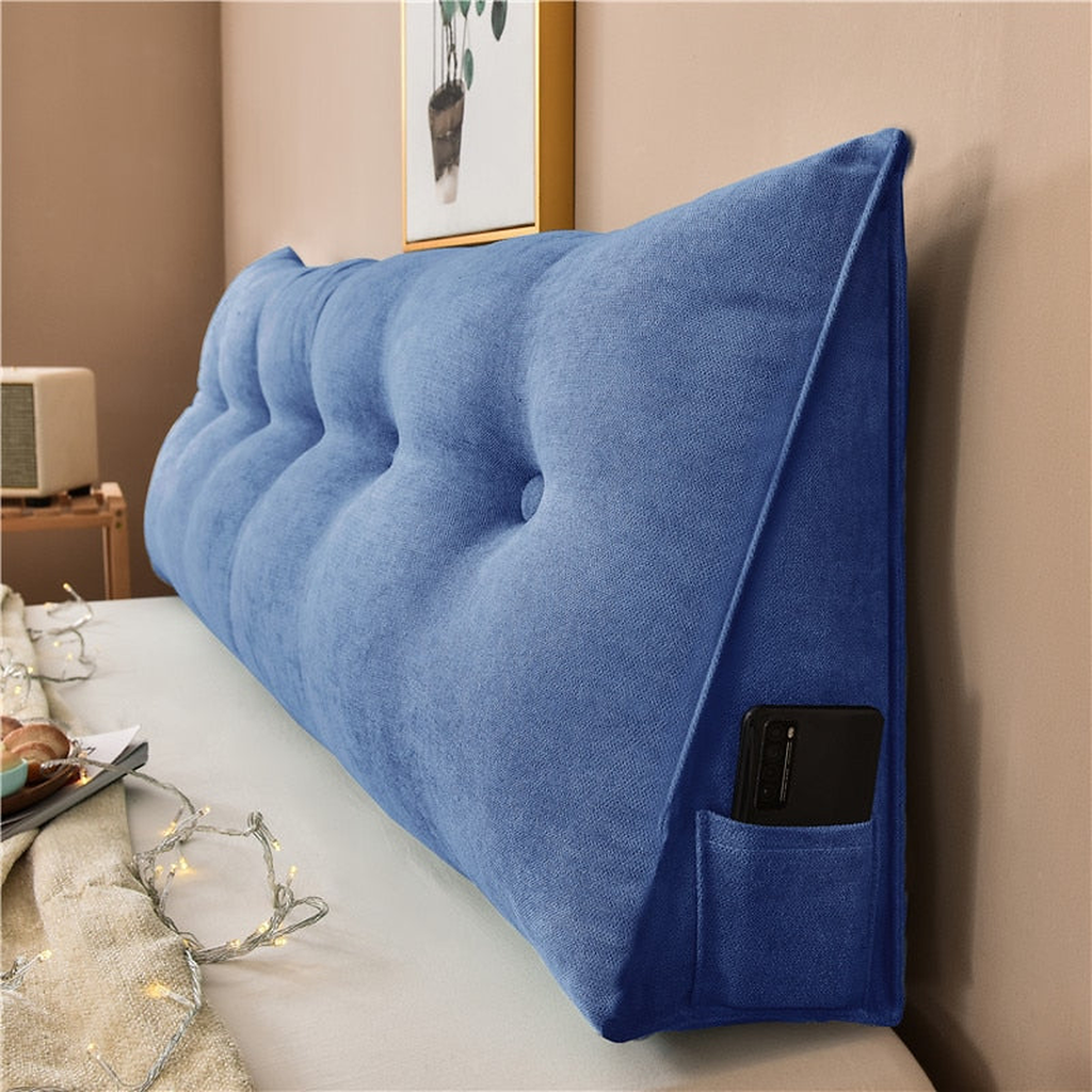 Coussin de chevet triangulaire bleu roi posé en travers d'un lit, capitonnage et flanc visibles