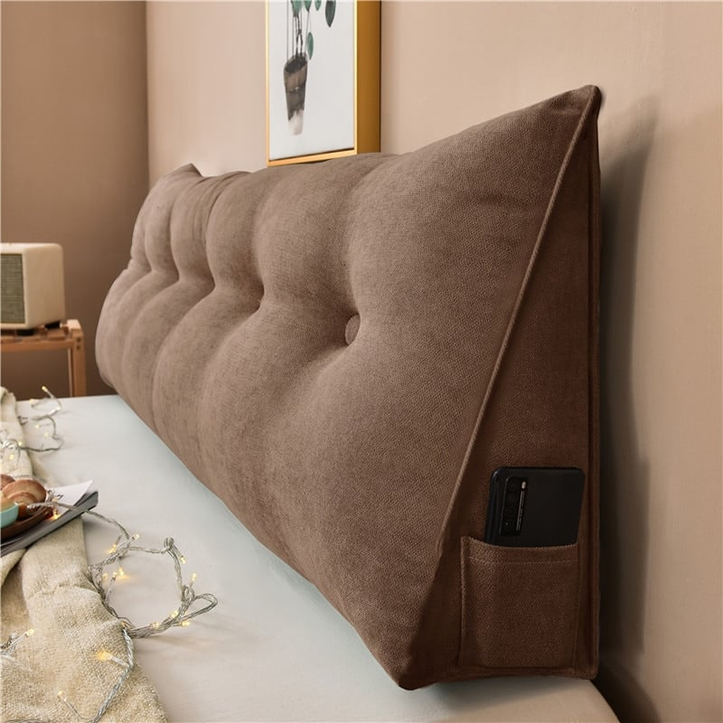 Coussin de chevet triangulaire brun chocolat posé en travers d'un lit, capitonnage et flanc visibles