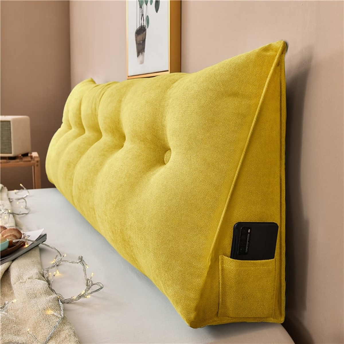 Coussin de chevet triangulaire jaune moutarde posé en travers d'un lit, capitonnage et flanc visibles