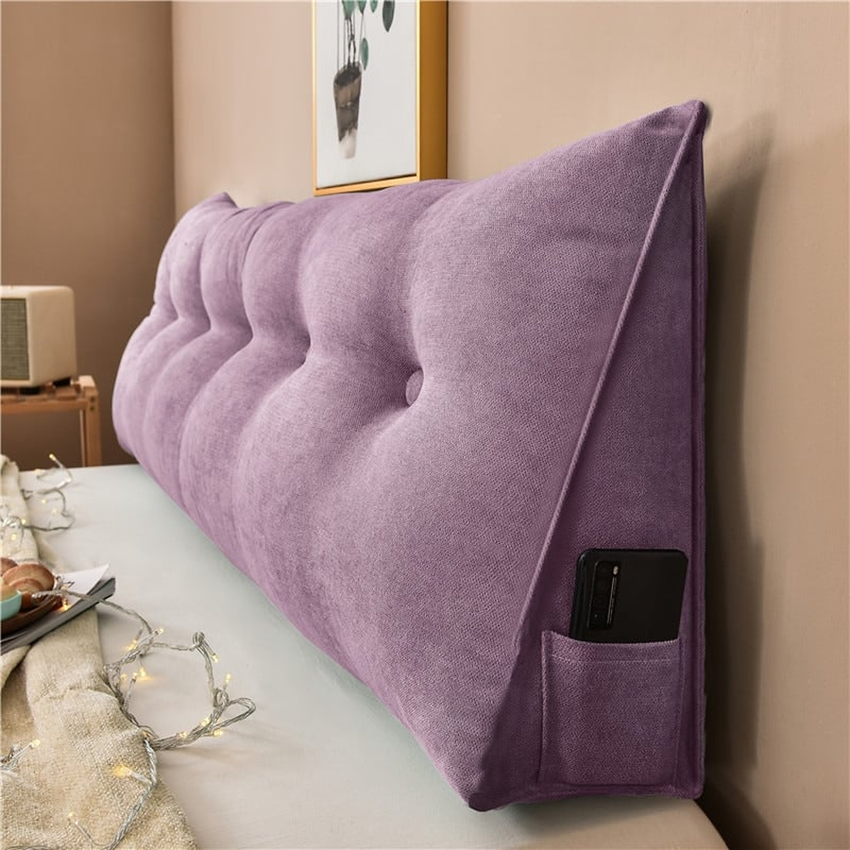 Coussin de chevet triangulaire violet parme posé en travers d'un lit, capitonnage et flanc visibles
