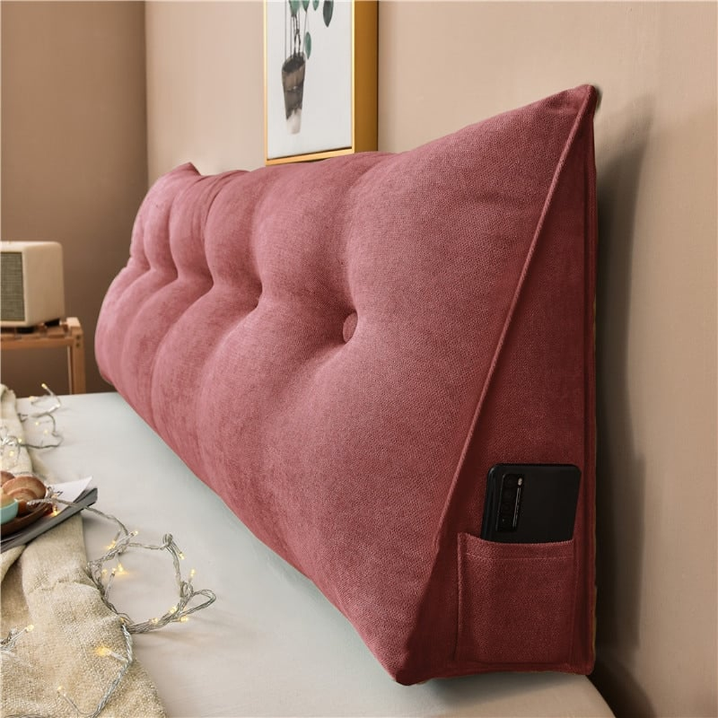 Coussin de chevet triangulaire rouge brique posé en travers d'un lit, capitonnage et flanc visibles