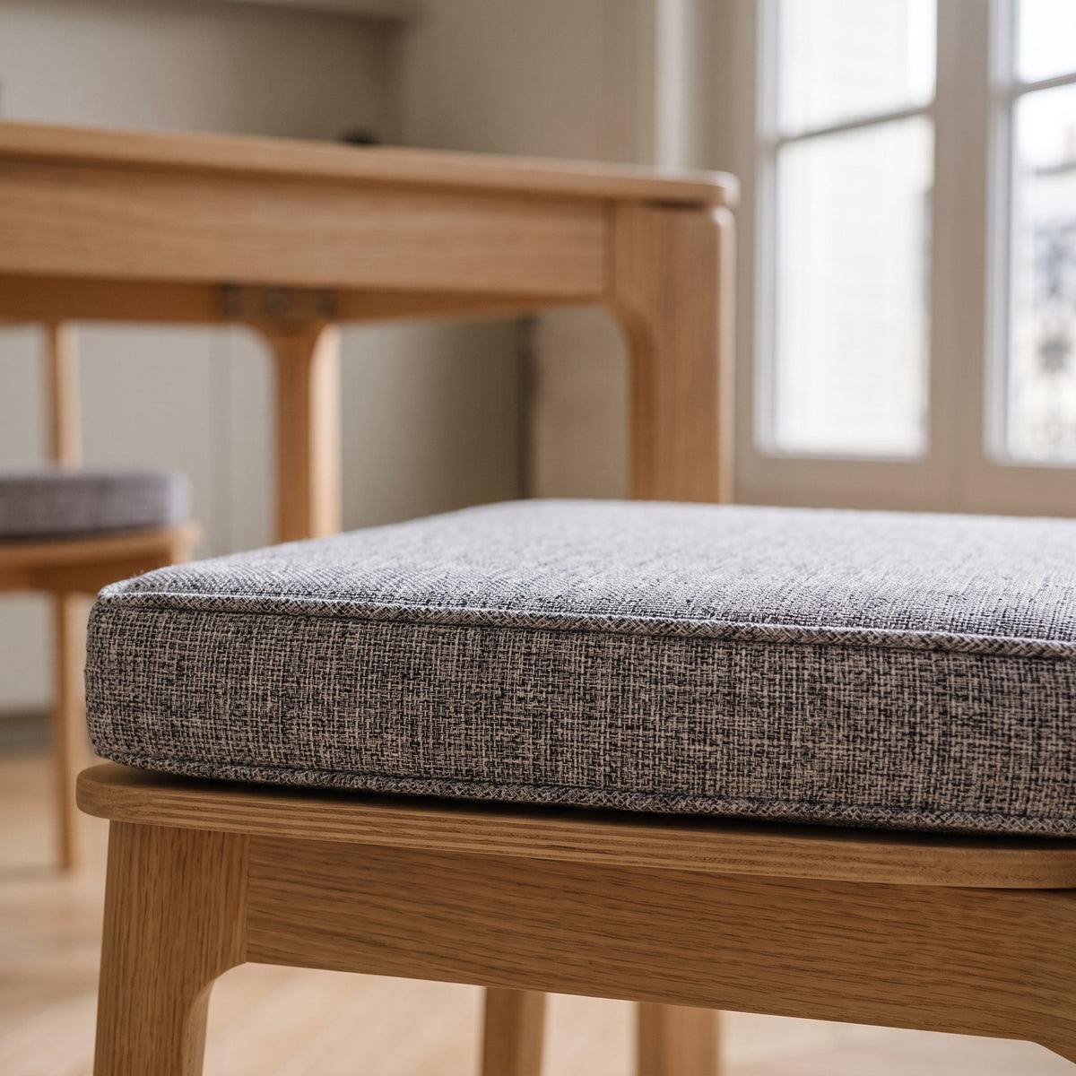 Coussin de sol gris clair vu de profil sur l'assise d'une chaise en bois Image