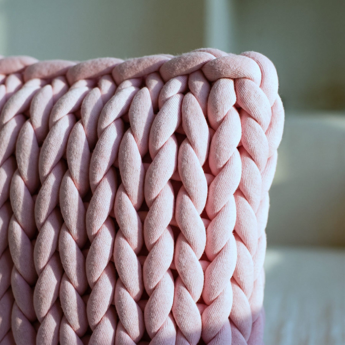 Coin d'un coussin grosses mailles rose poudré, tranche et croisement des cordons Image