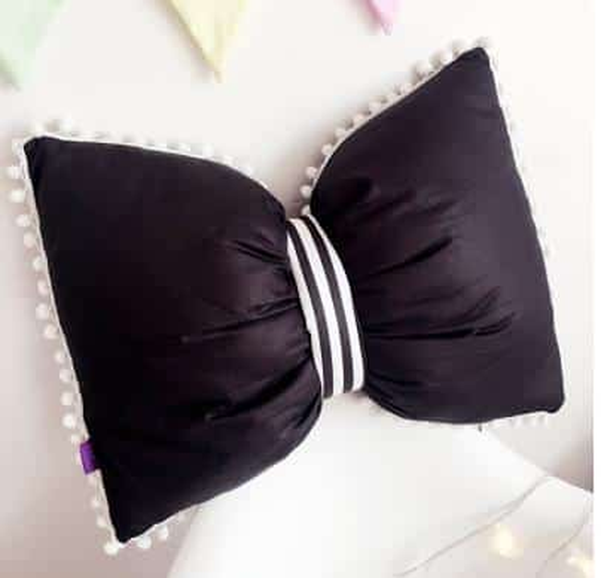 Coussin nœud papillon noir, posé sur un canapé gris