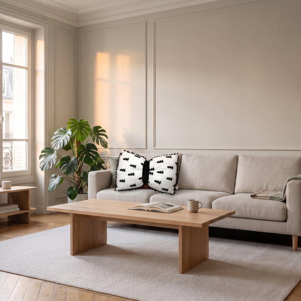 Coussin nœud papillon blanc à sapins noirs sur un canapé clair