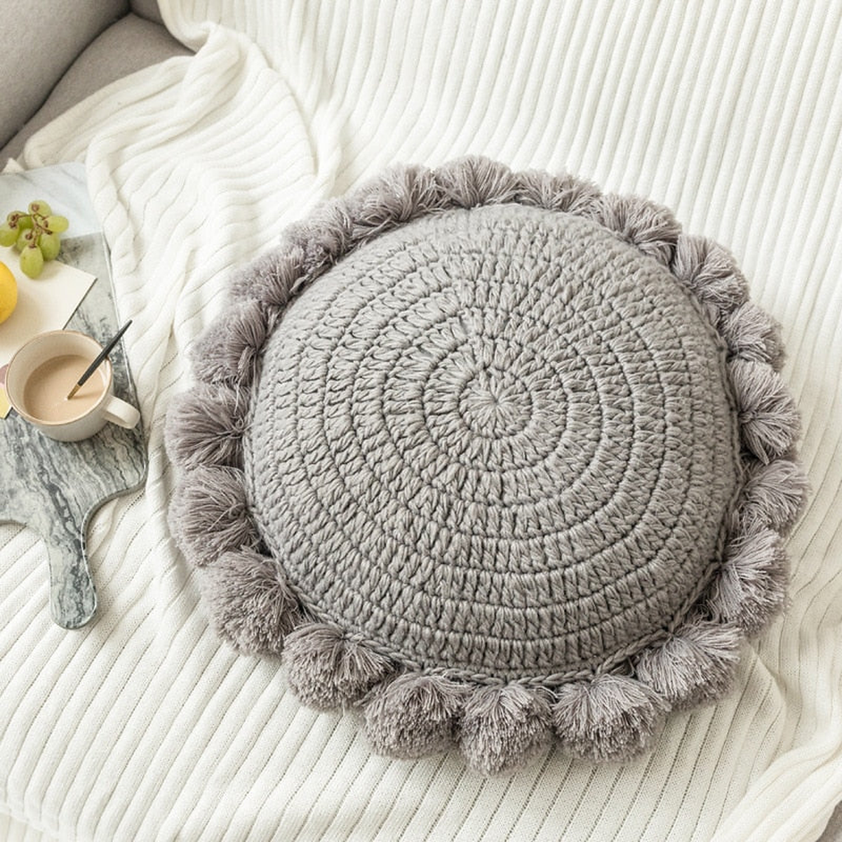 Coussin rond tricoté bordé de pompons, coloris Gris