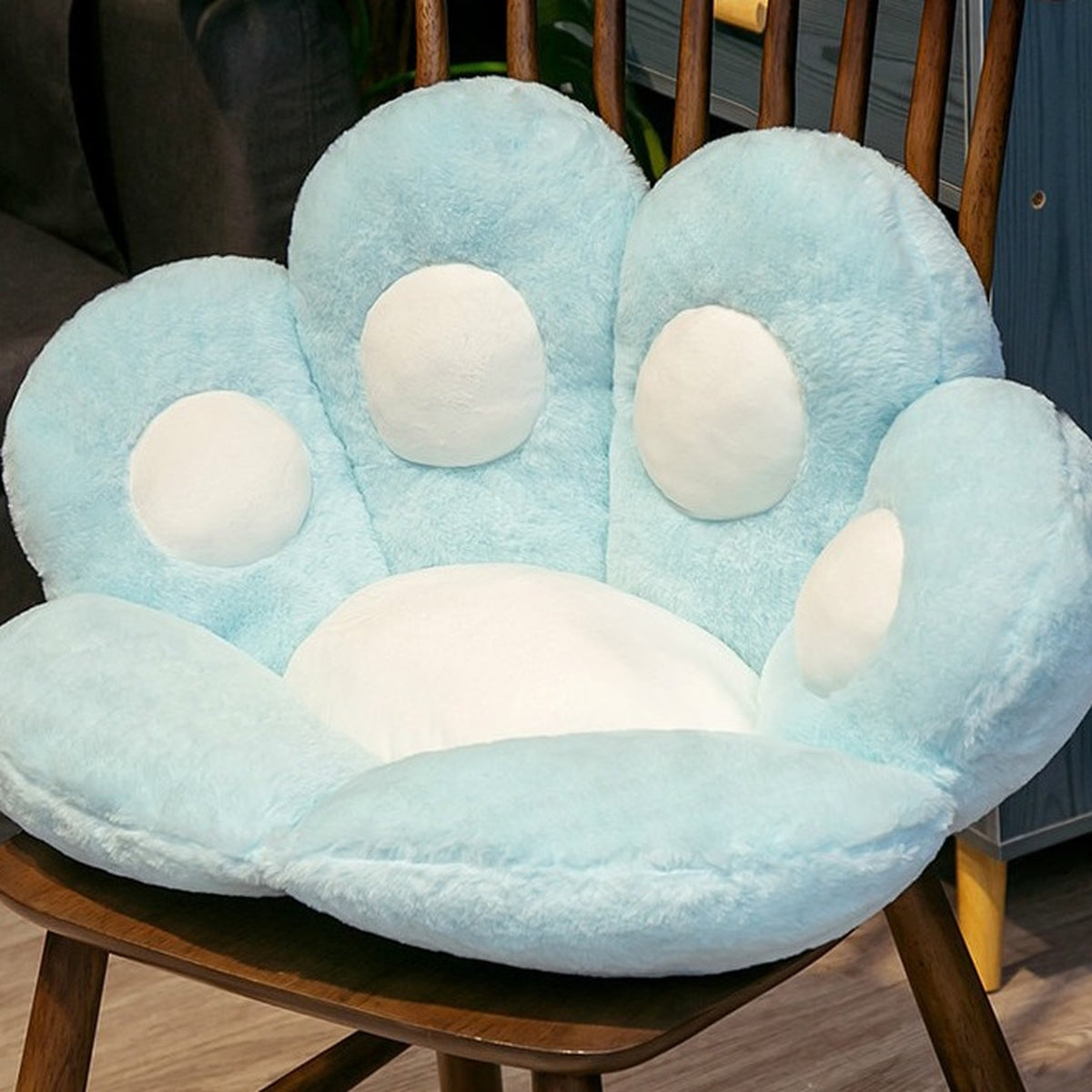 Coussin de sol patte de chat bleu de 45 cm posé sur une chaise en bois