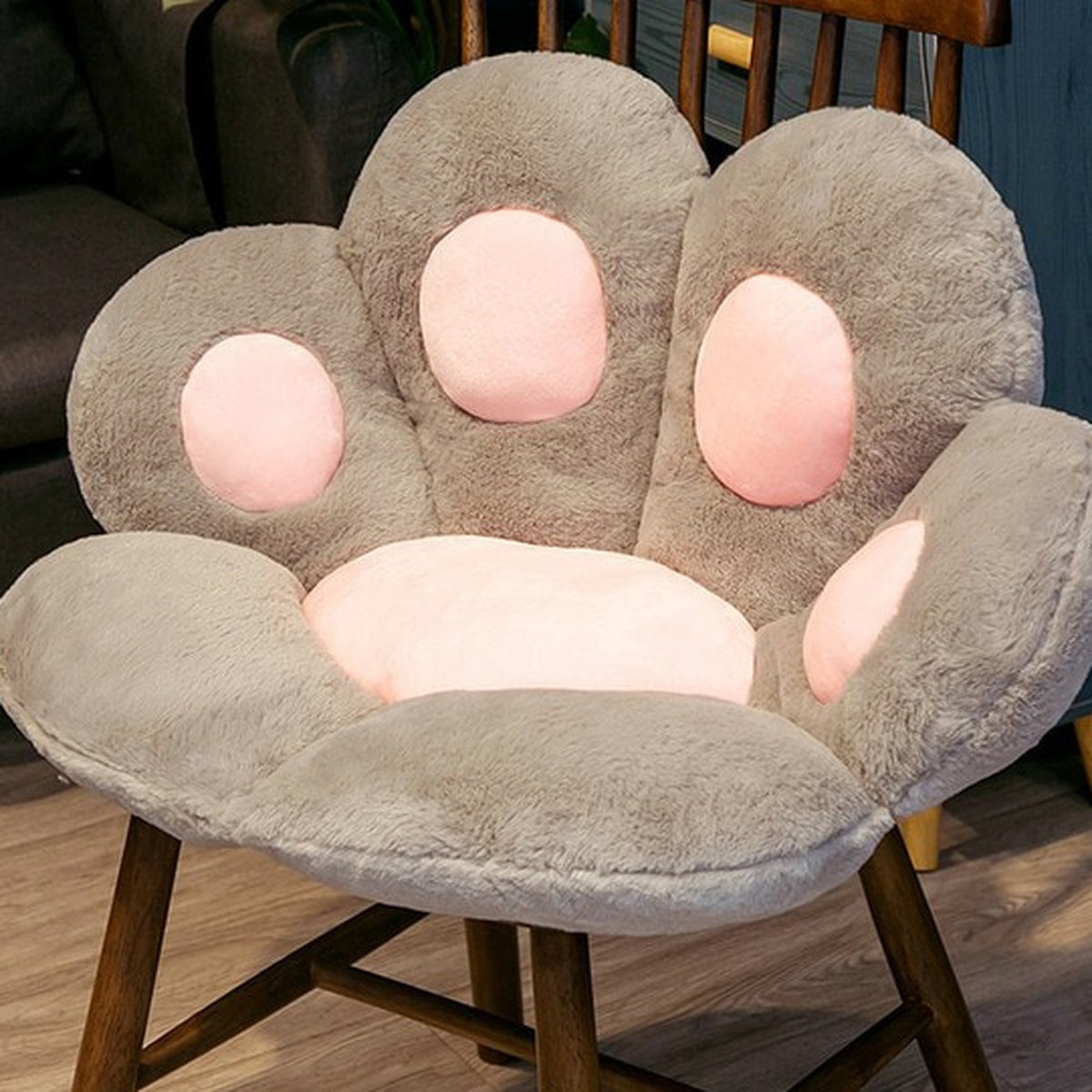 Coussin de sol patte de chat gris de 45 cm posé sur une chaise en bois