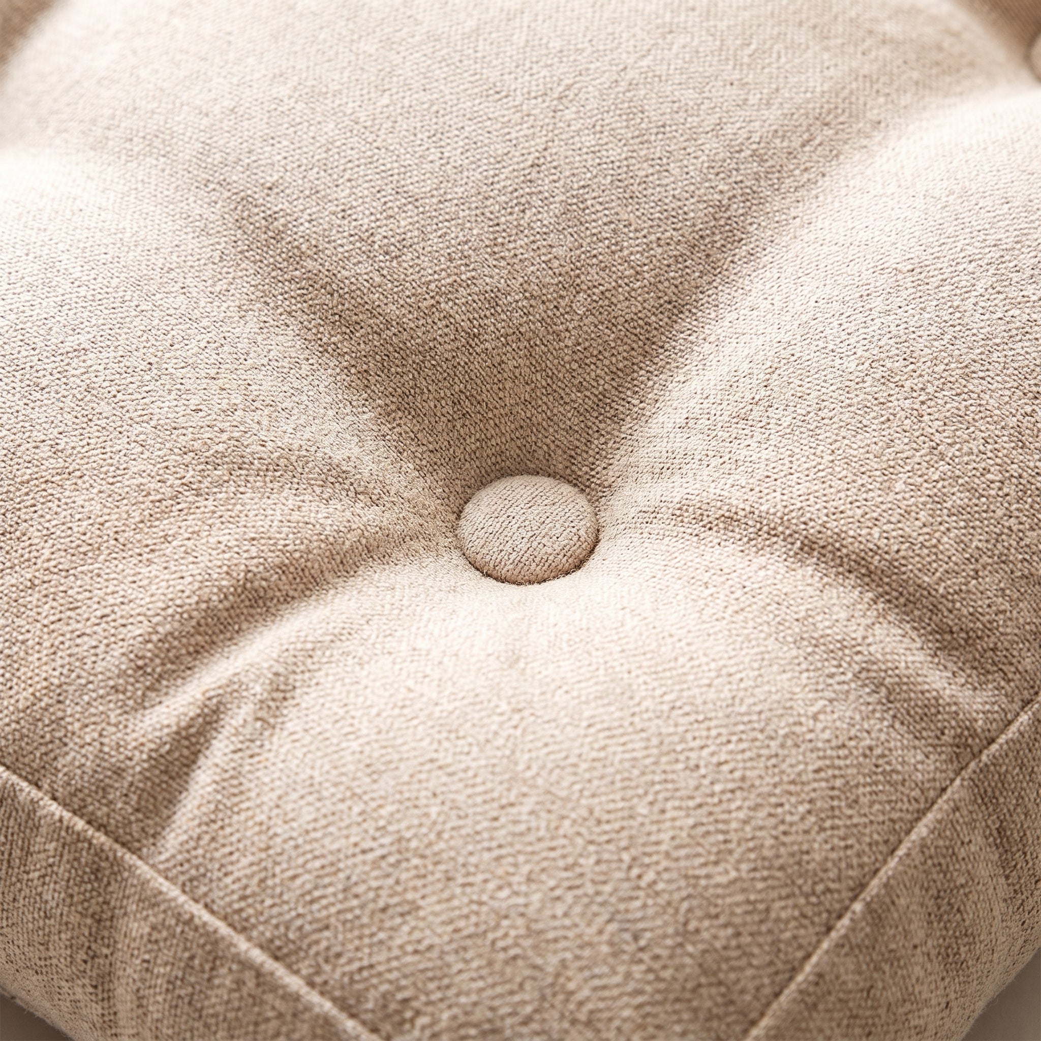 Détail du bouton central et des plis du coussin de sol rond beige Image
