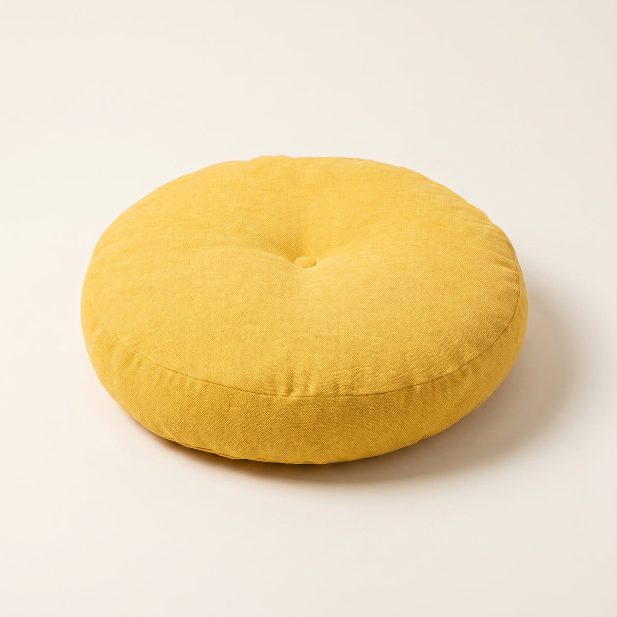 Coussin de sol rond jaune avec bouton central et couture latérale