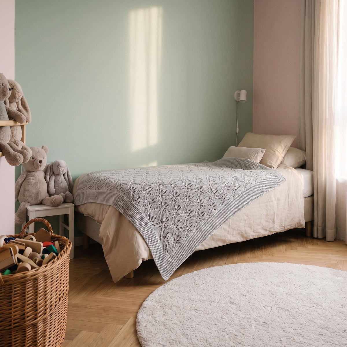 Couverture pour bébé en coton à maille pointelle, coloris gris, posée sur le lit d'une chambre d'enfant