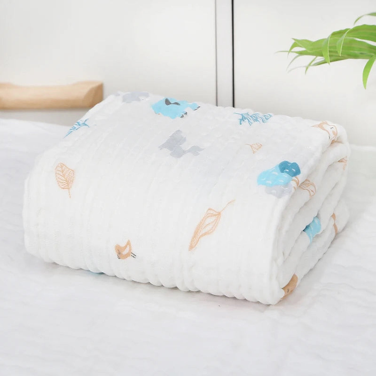 Couverture bébé pliée à motif de hiboux bleus et feuilles beige