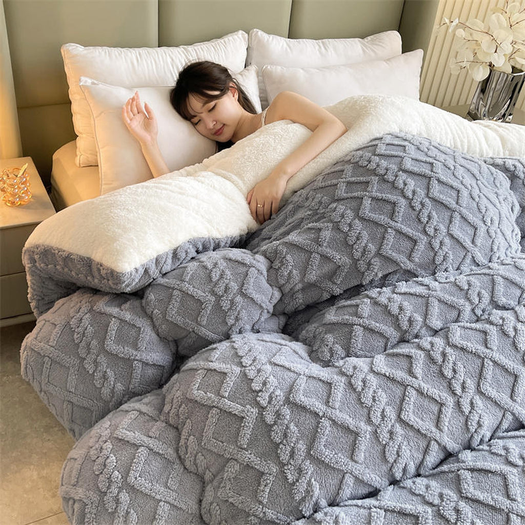 Couverture épaisse grise déployée sur un lit montrant son relief et sa face claire duveteuse