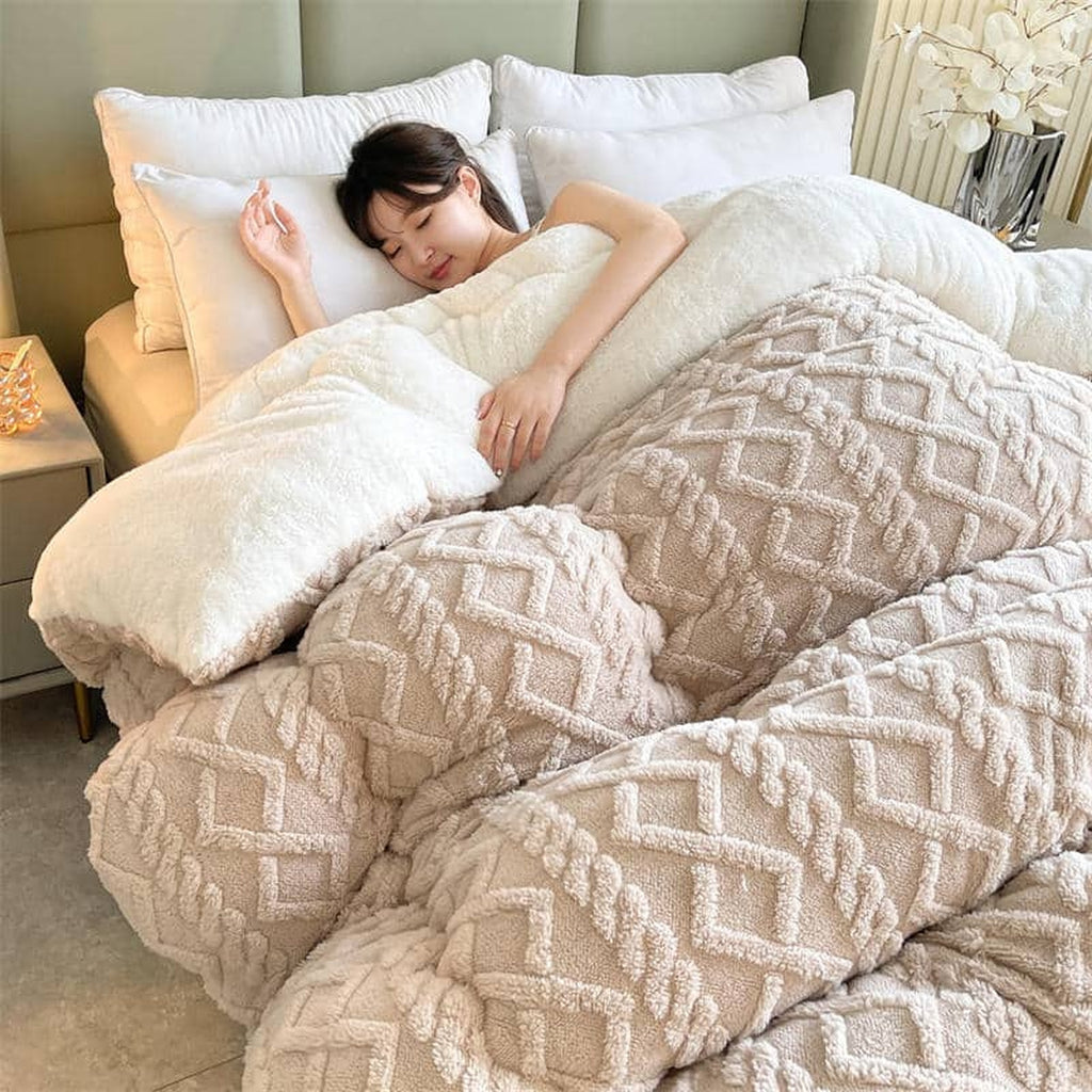 Couverture épaisse beige déployée sur un lit double avec sa retombée visible