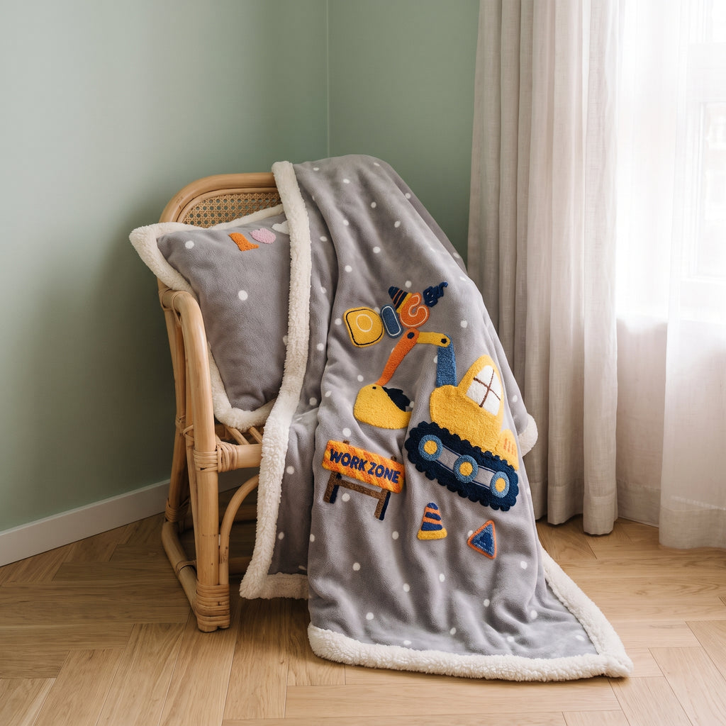Couverture bébé grise à bordure écrue drapée sur un fauteuil